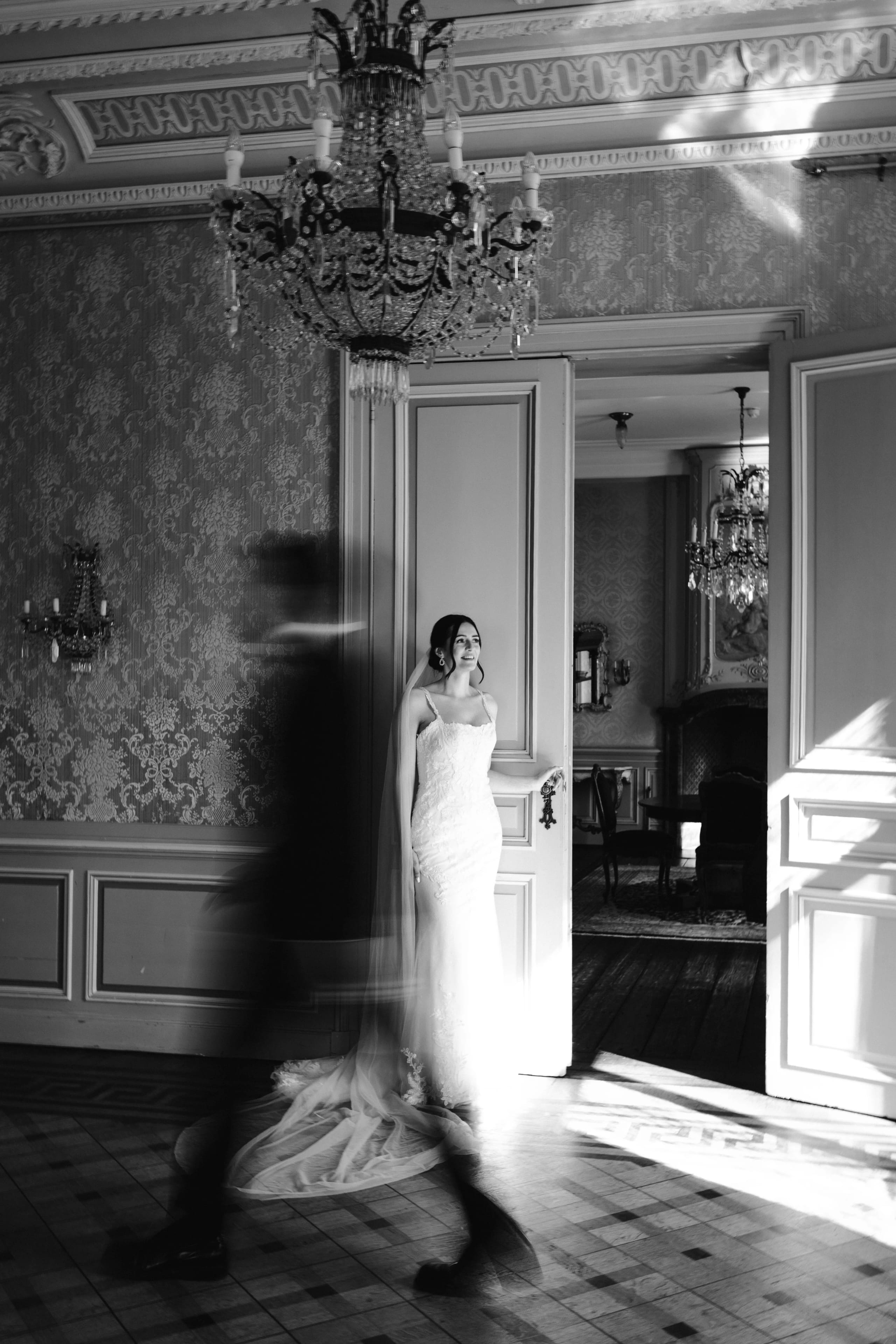 Een bruid in een prachtige, uitgebreide jurk staat in een elegante kamer met vintage decor, terwijl een mysterieuze schaduw van een andere persoon snel voorbij beweegt, wat een gevoel van beweging en intrige creëert.