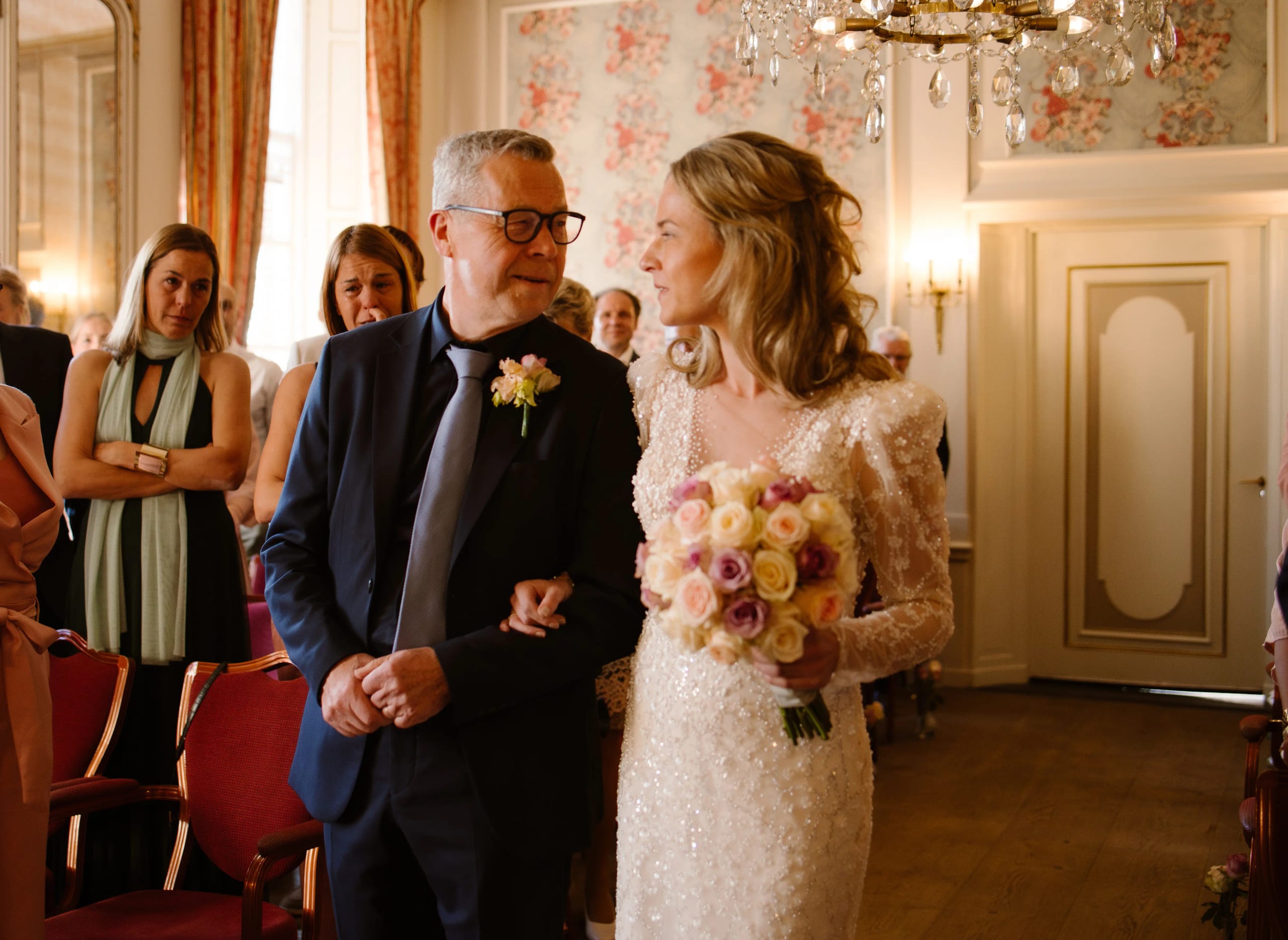 Vader geeft de lachende bruid in lovertjesjurk weg tijdens de huwelijksceremonie