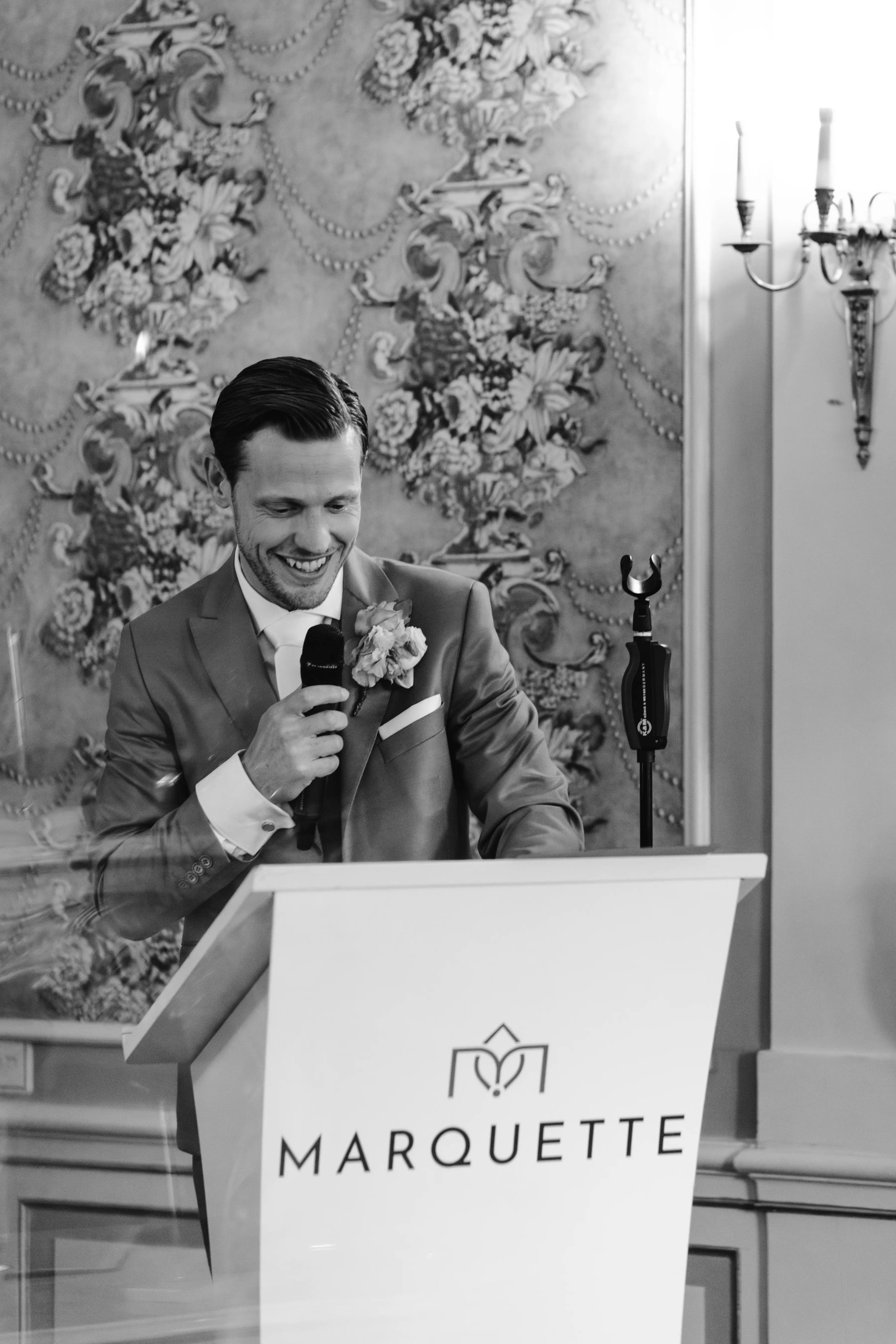 Zwart-wit foto van de bruidegom die een toespraak houdt achter een katheder
