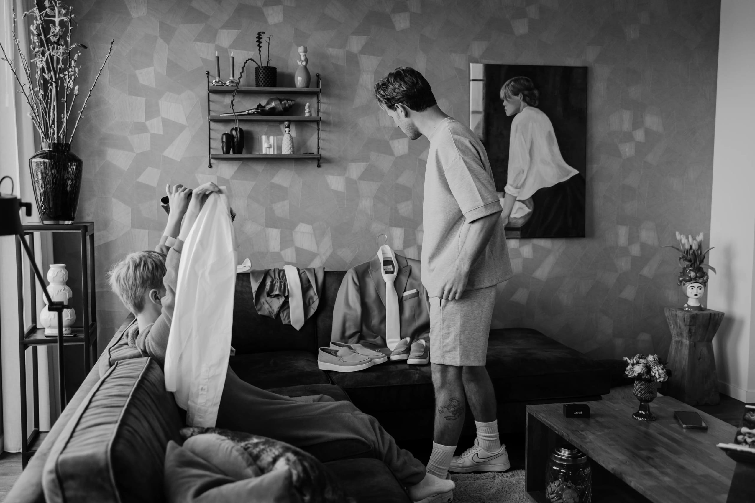 Zwart-wit foto van de bruidegom die zich aankleedt en voorbereidt op de trouwdag