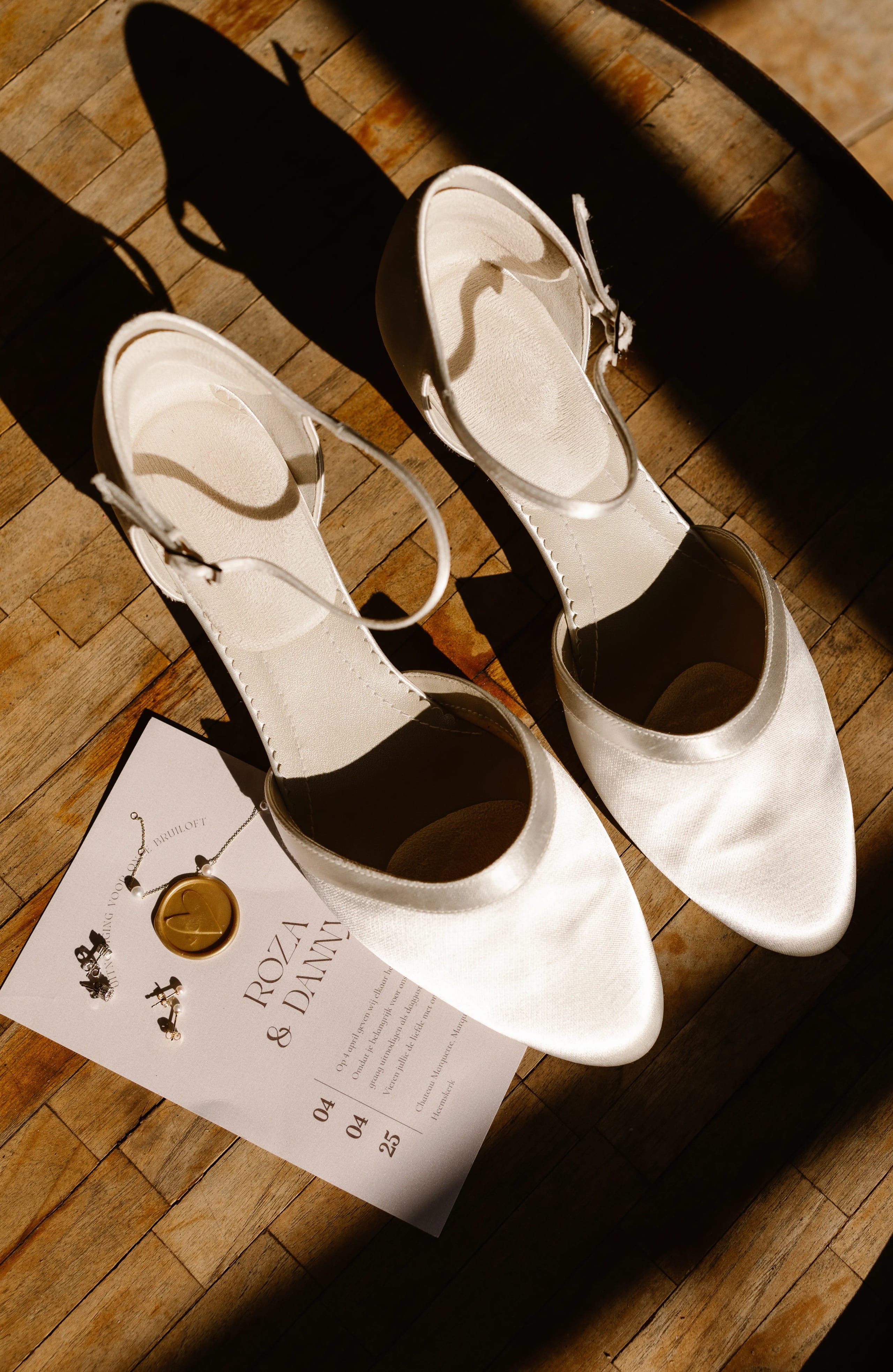 Elegante crèmekleurige bruidsschoentjes en een stijlvolle trouwkaart met lakzegel
