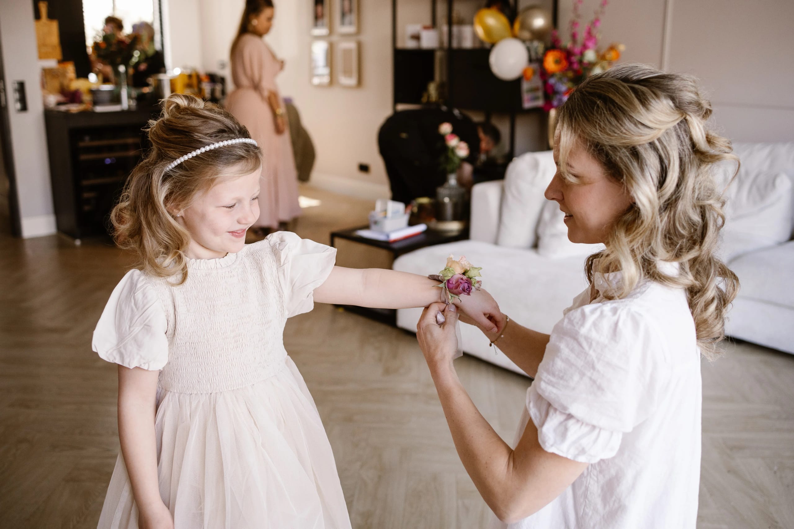Bruid helpt het bloemenmeisje met het omdoen van een bloemenarmbandje