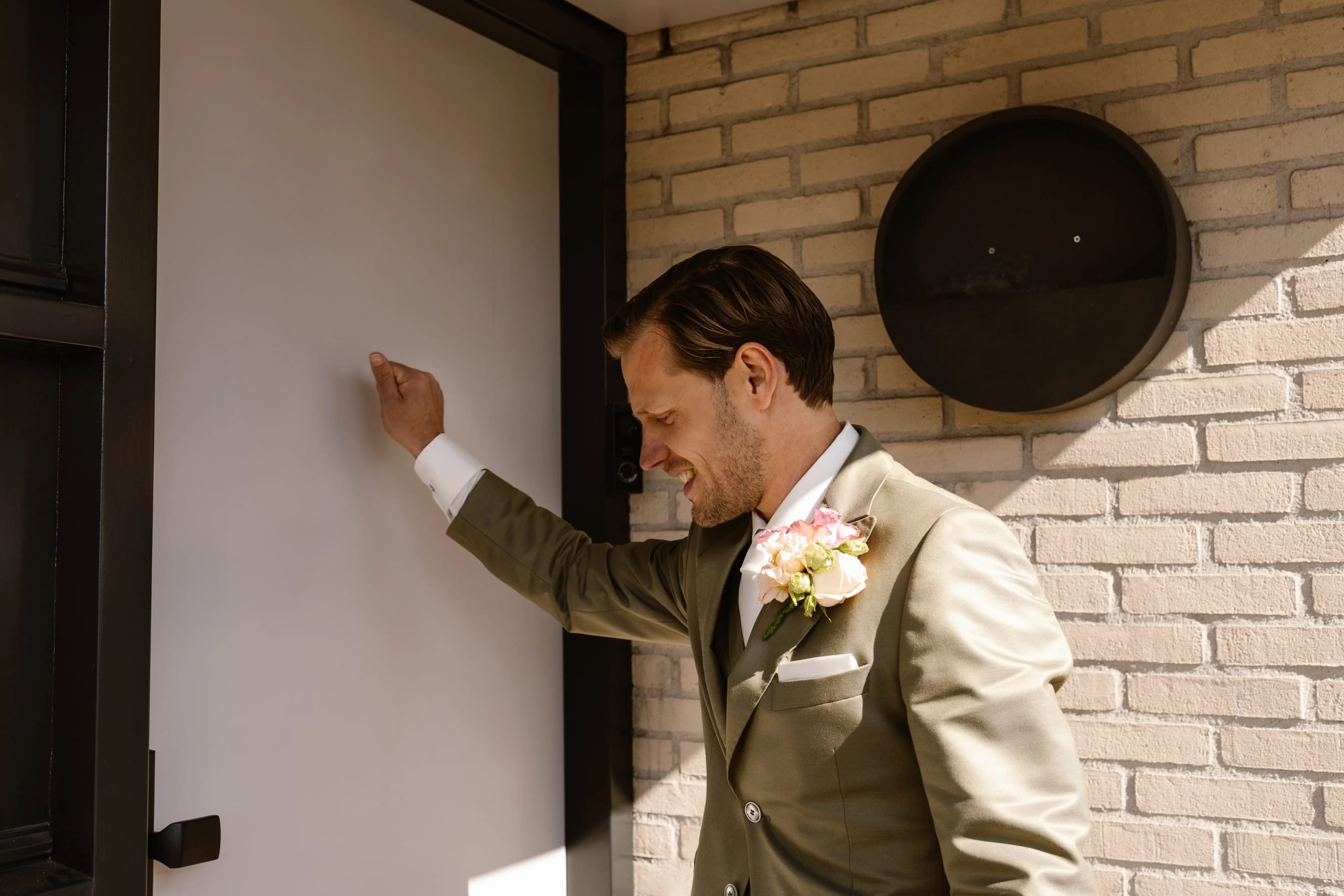 Ontspannen moment van de bruidegom leunend tegen een bakstenen muur