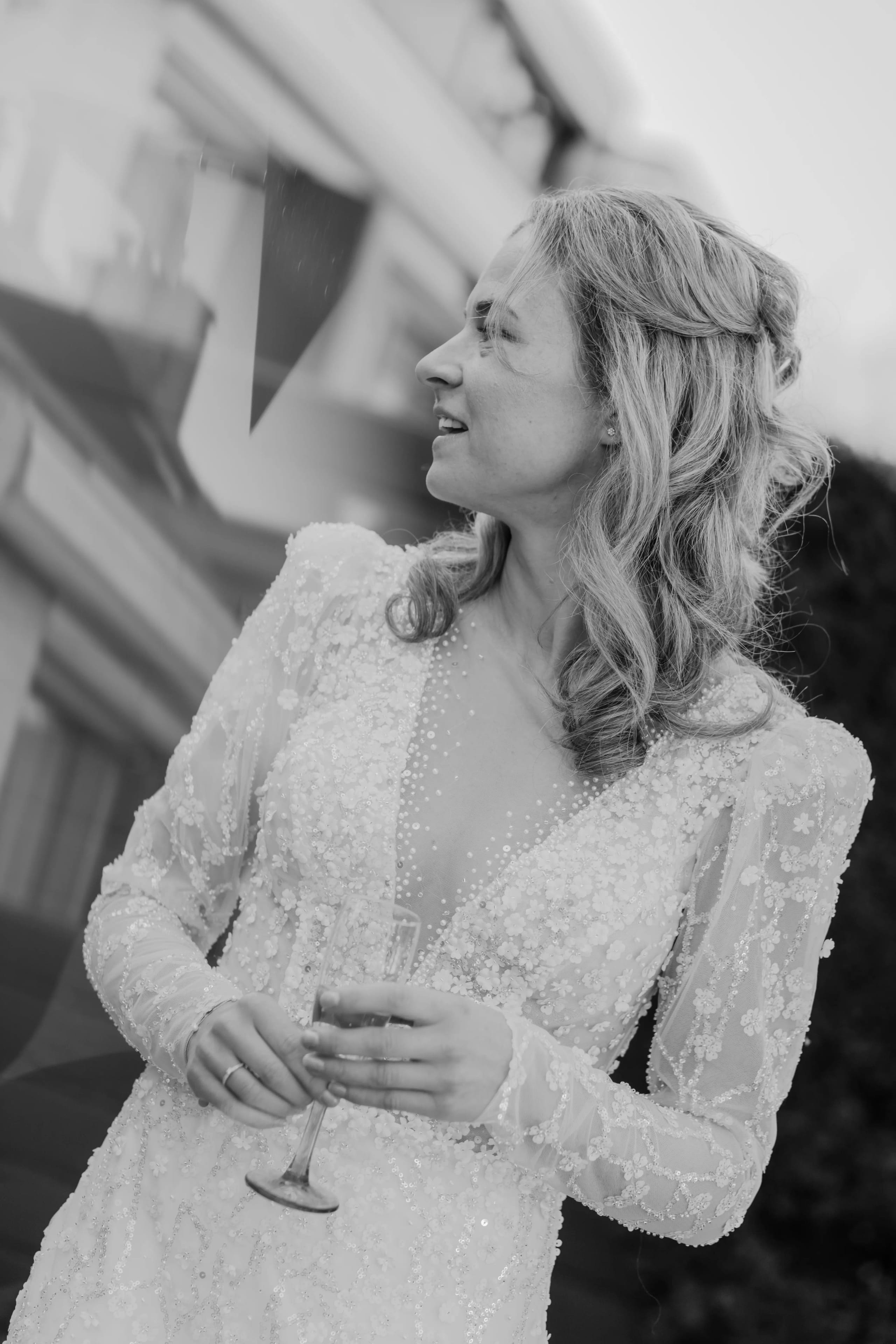 Zwart-wit foto van de gelukkige bruid met een glimlach en champagneglas in haar hand