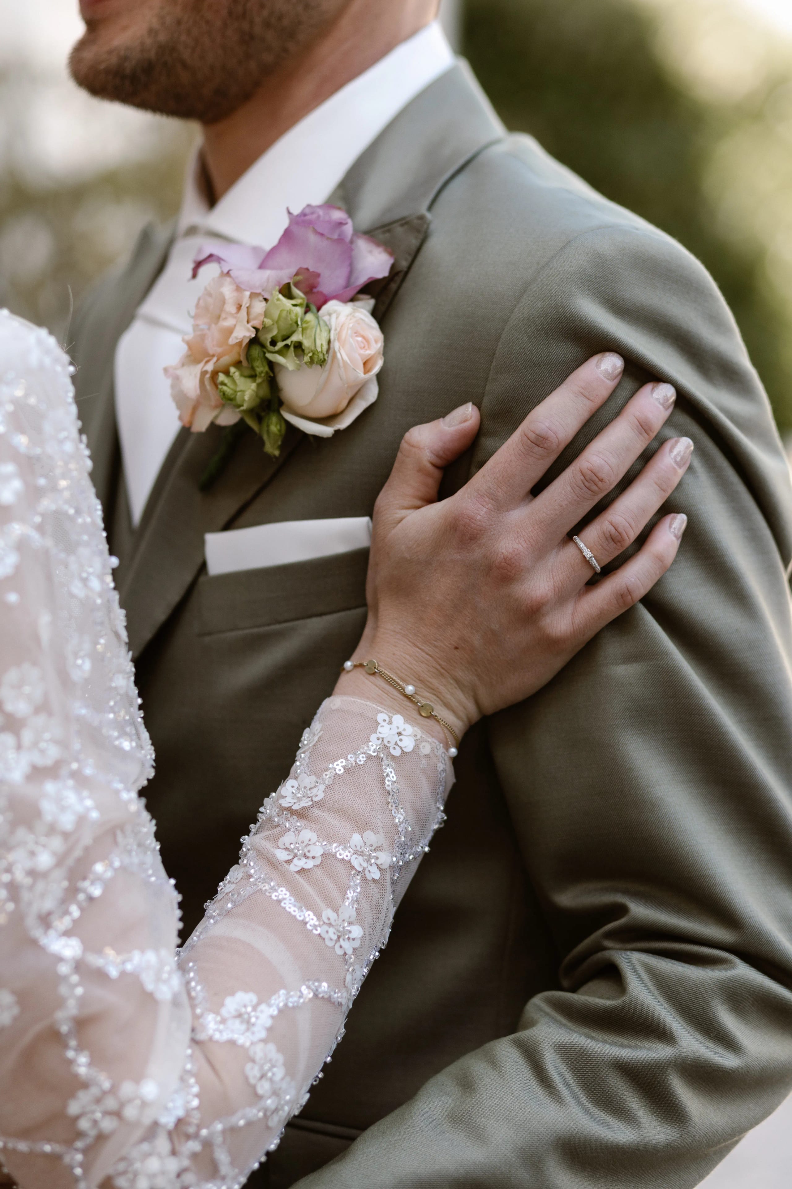 Detailfoto van de hand van de bruidegom met trouwring rustend op de rug van de bruid