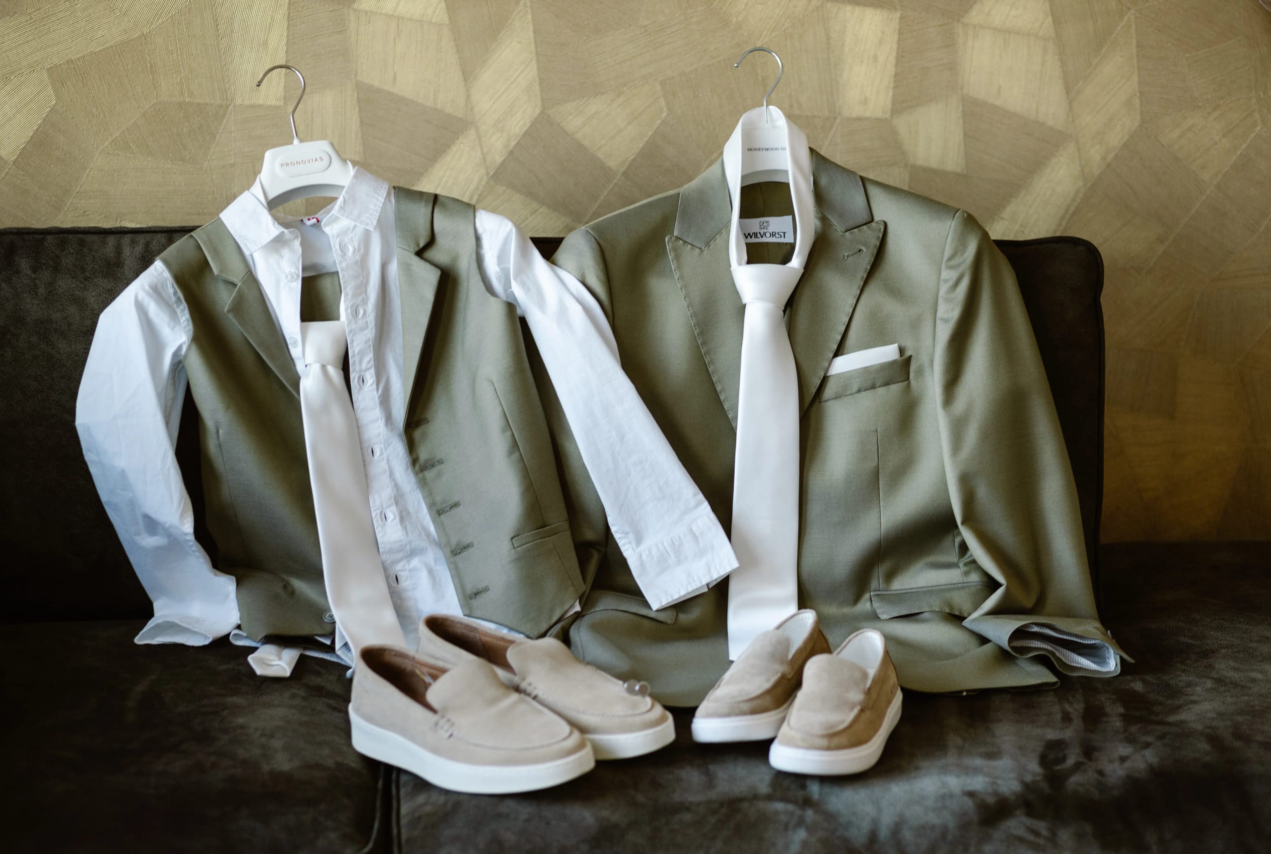 Details van het saliegroene trouwpak van de bruidegom met witte das en instappers op bed