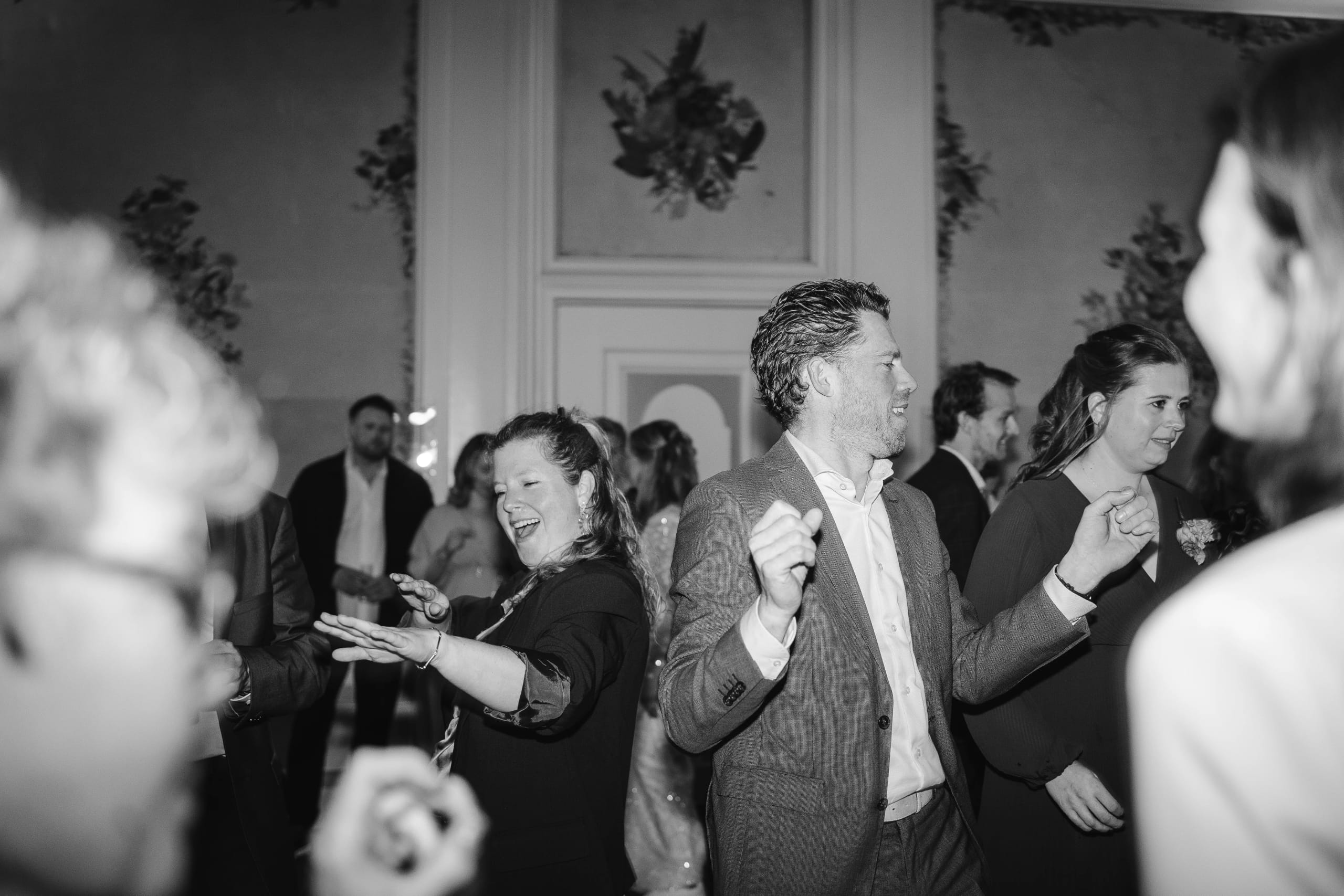 Zwart-wit momentopname van feestende en dansende gasten op de bruiloft dansvloer