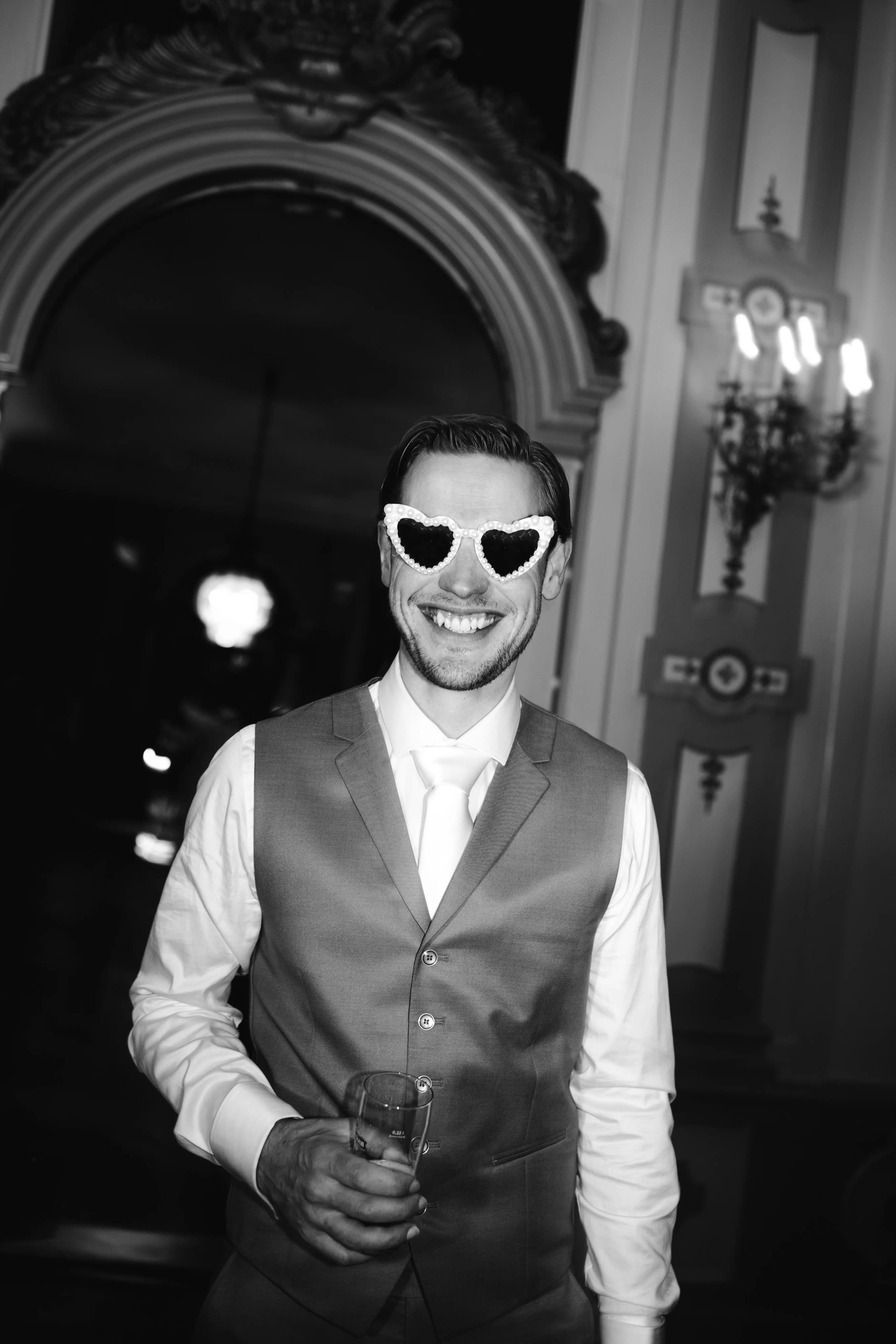 Zwart-wit partyshot van de lachende bruidegom vol in zijn element feestend met vrienden