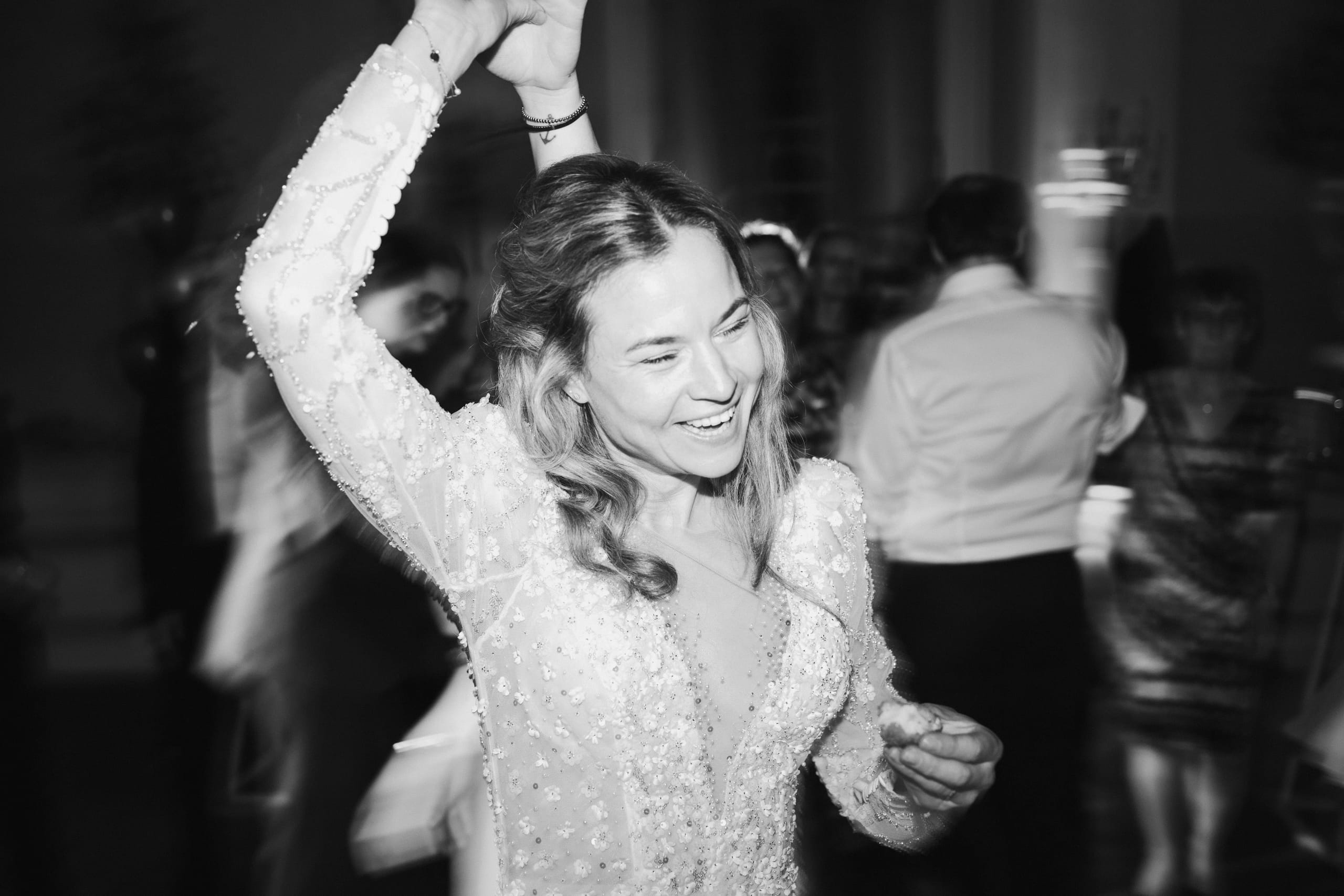 Zwart-wit actieshot van blije dansende bruid tijdens huwelijksfeest in het kasteel
