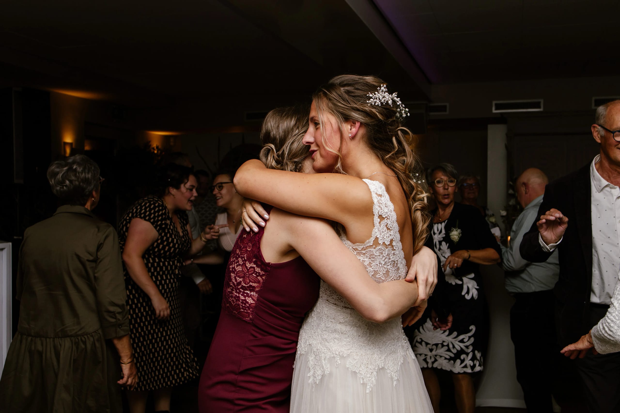 Emotionele knuffel tussen de bruid en een bruiloftsgast tijdens de receptie