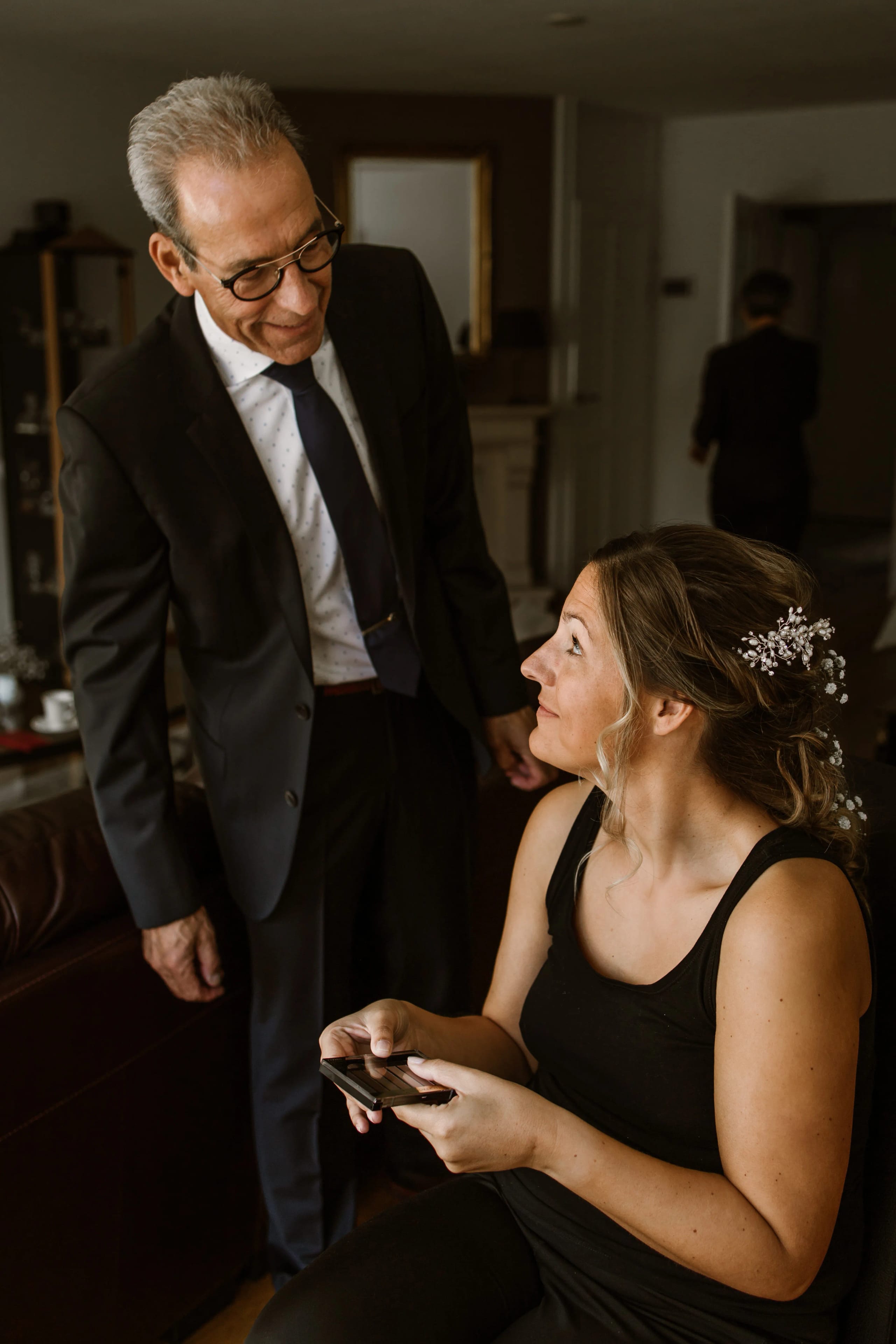 De vader van de bruid in een donker pak kijkt trots en liefdevol naar zijn dochter