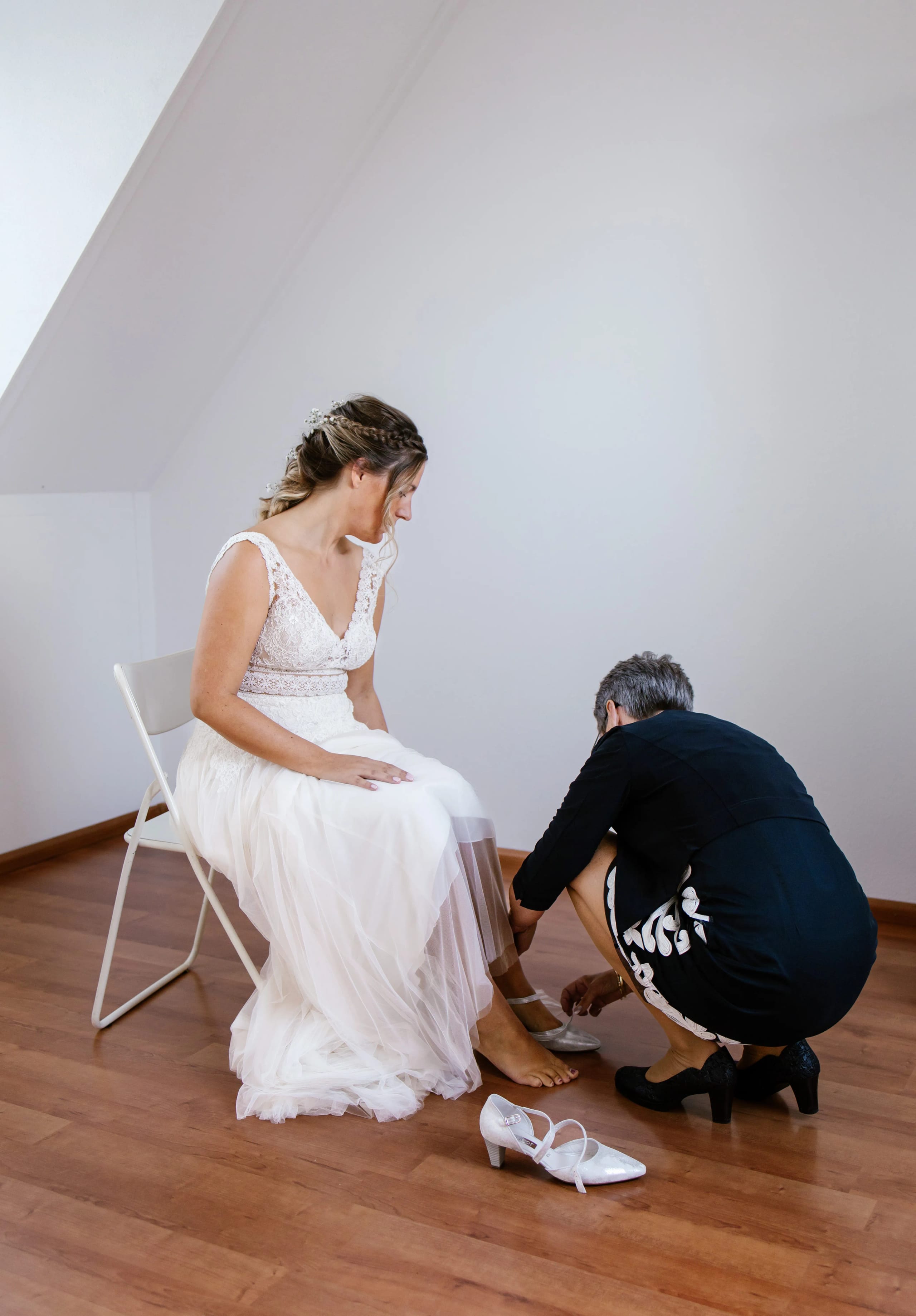 Een intiem moment waarbij een gast de schoen van de bruid helpt aan te trekken
