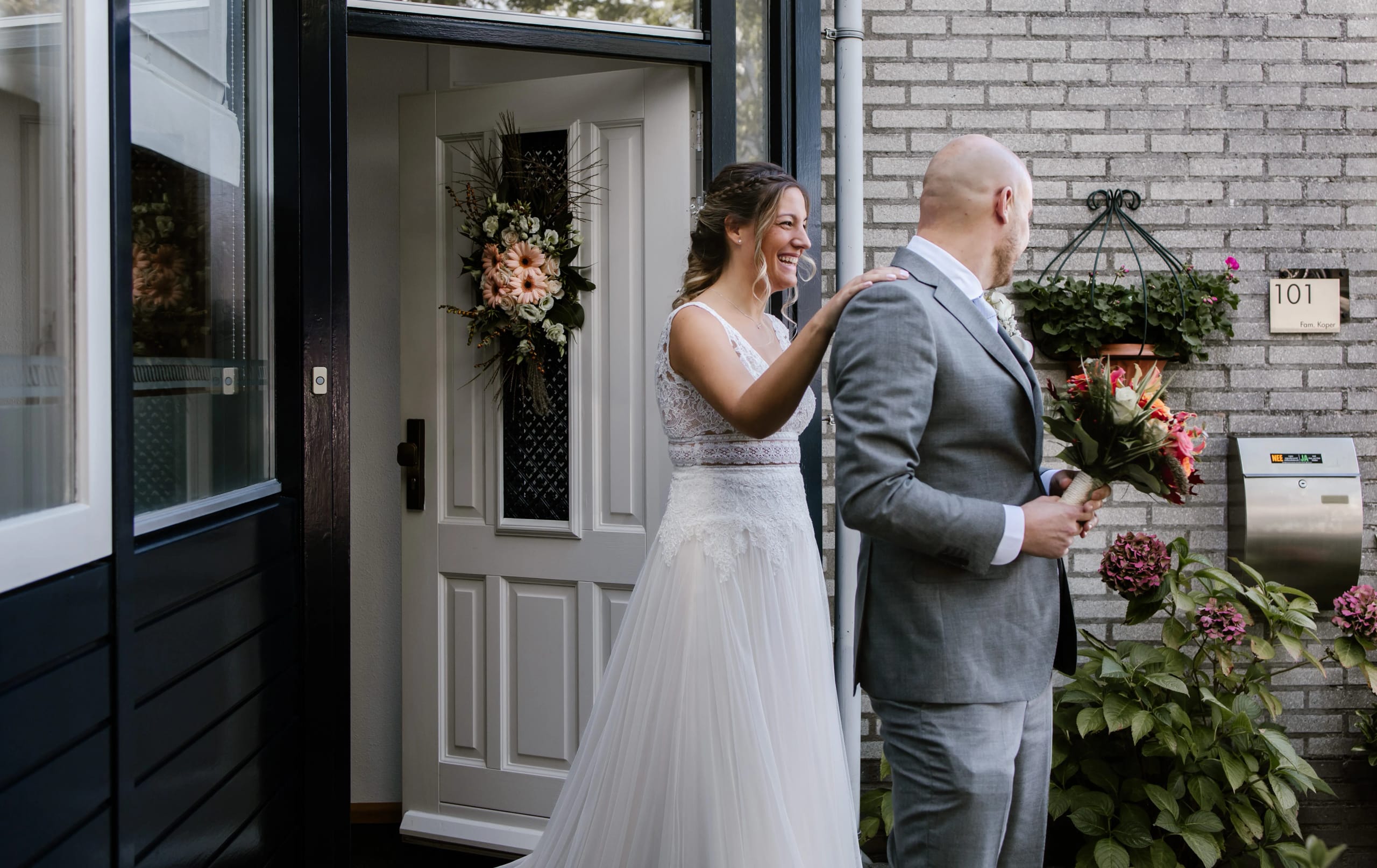 De bruid raakt liefdevol de schouder van de bruidegom aan bij de eerste ontmoeting bij de voordeur