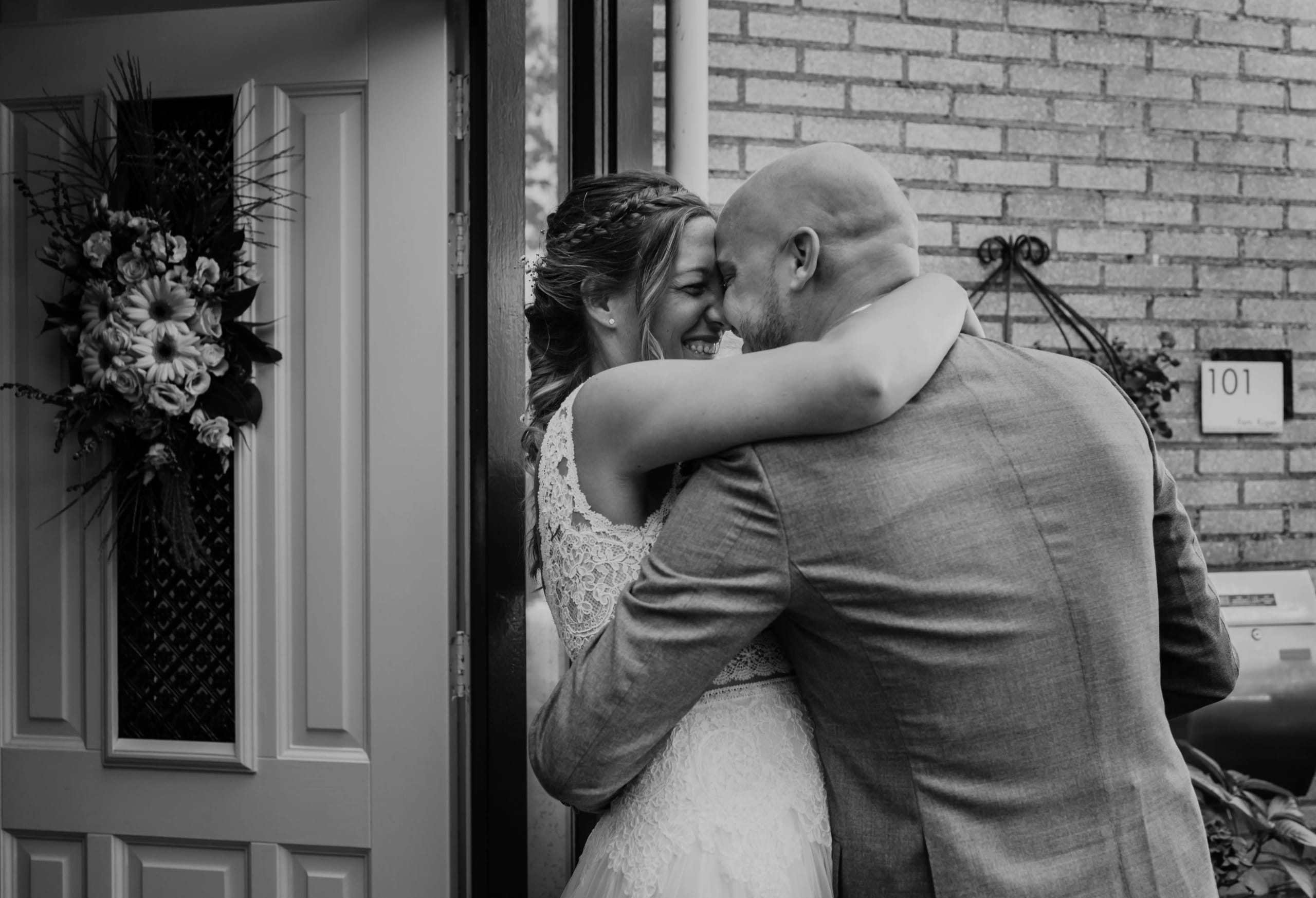 Zwart-wit close-up van de bruid en bruidegom die elkaar teder omhelzen en lachen