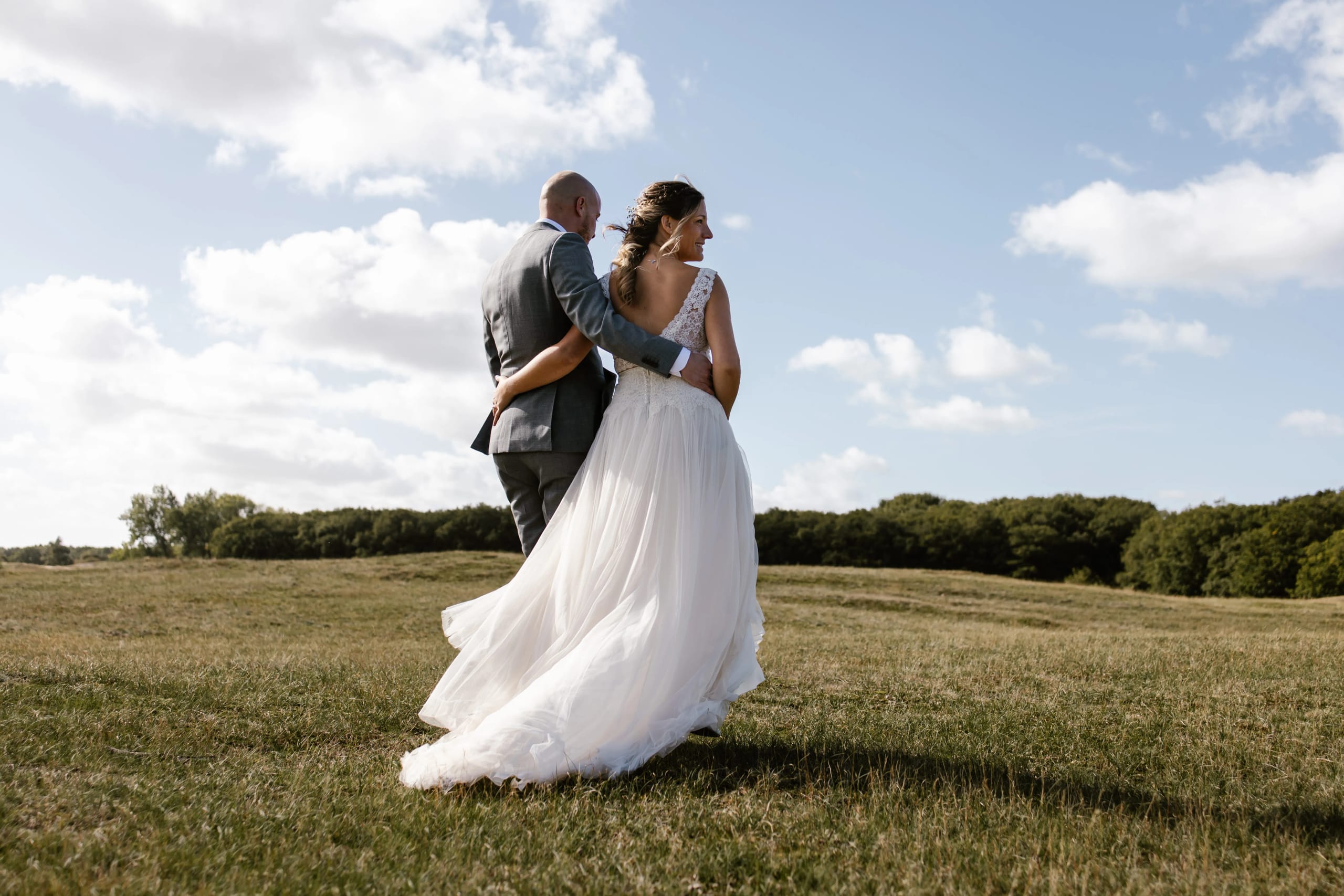 Denise en Hein staan rug aan rug en kijken uit over het zonnige landschap