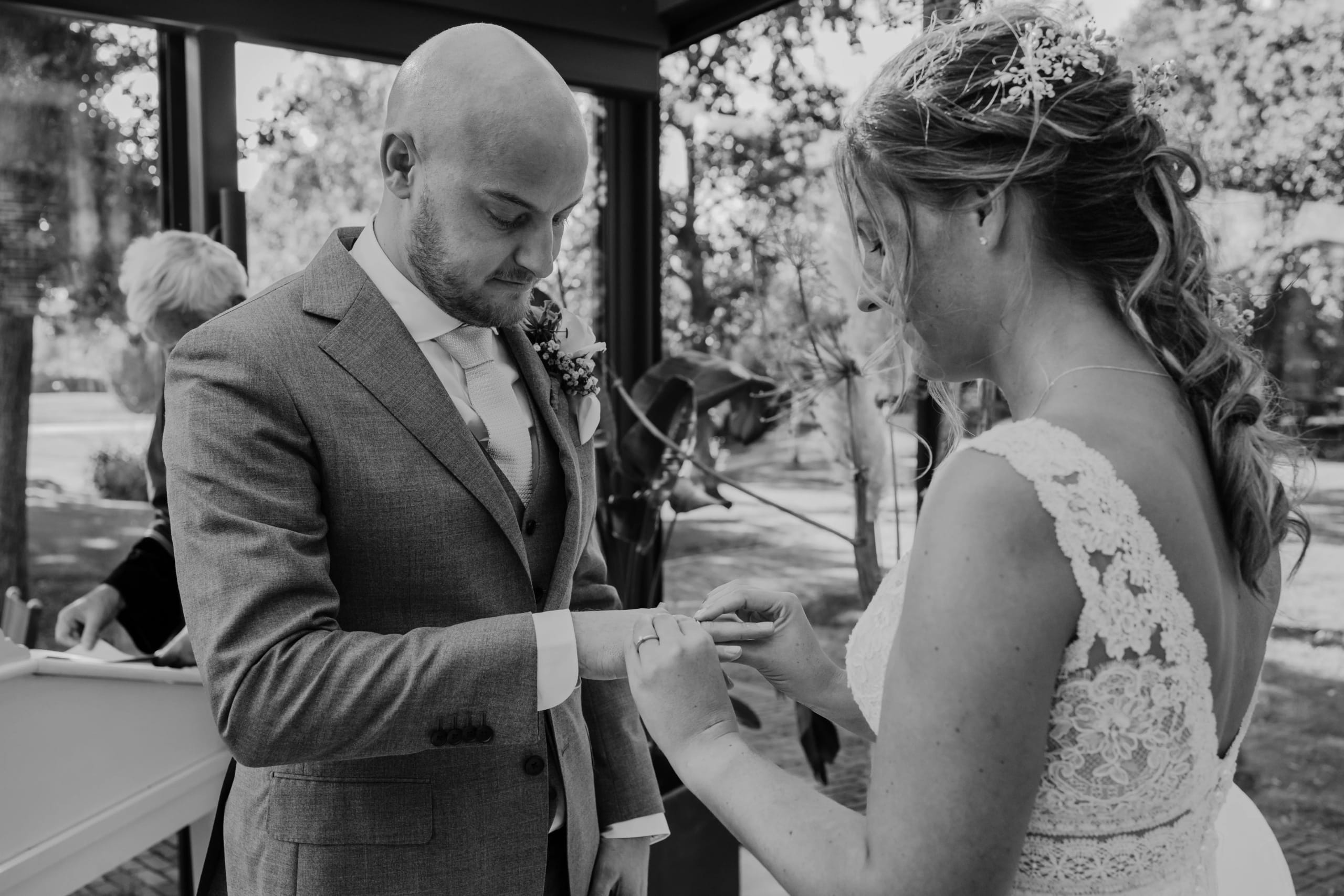 Zwart-wit detail van de bruid die de trouwring om de vinger van de bruidegom schuift