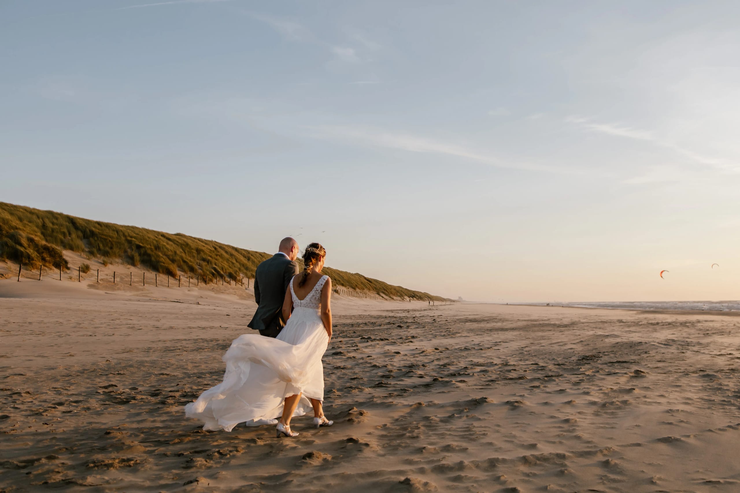 Hein en Denise lopen hand in hand over het uitgestrekte strand bij de zee