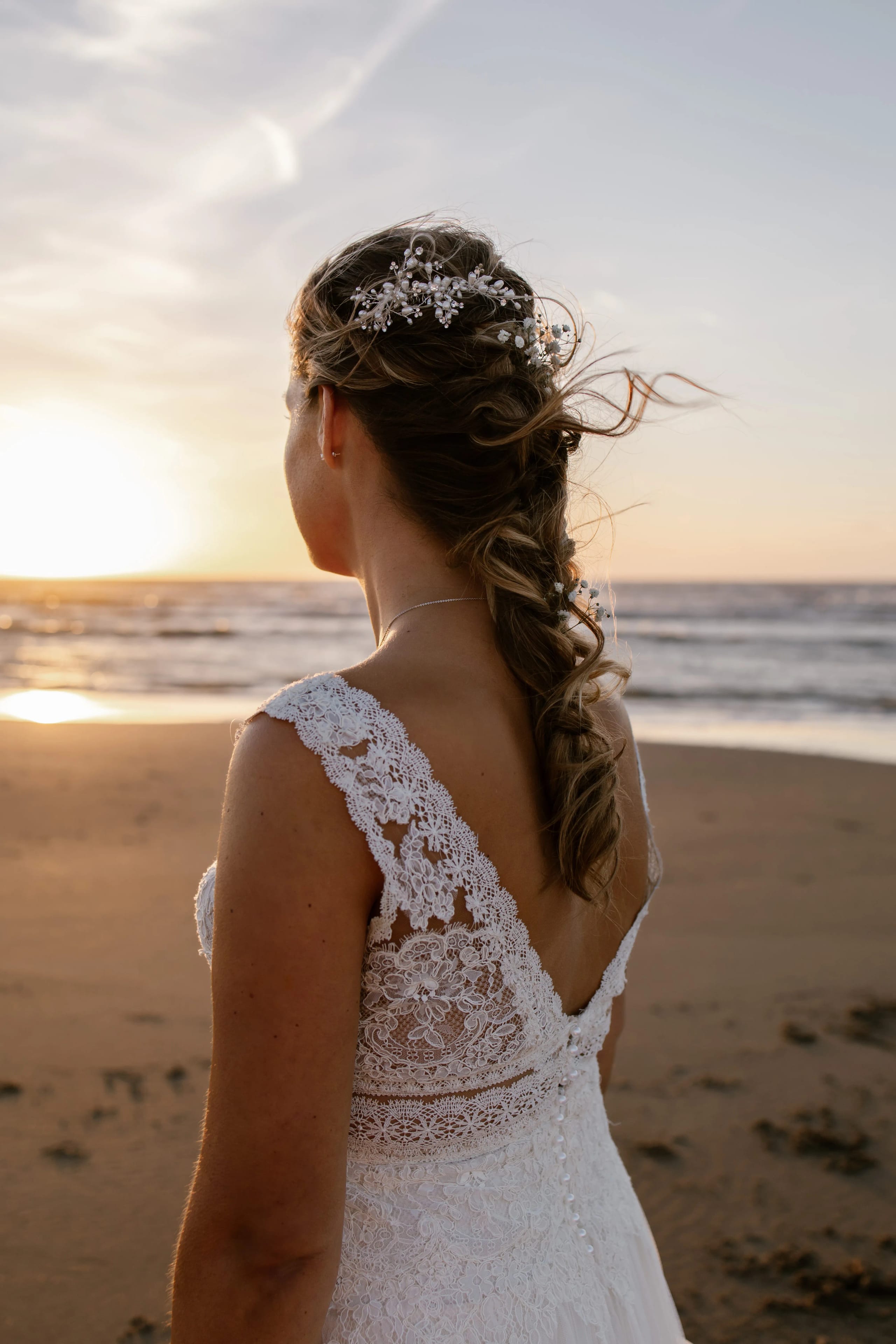 Zwart-wit detailopname van de wapperende sleep van de trouwjurk op het donkere strandsand
