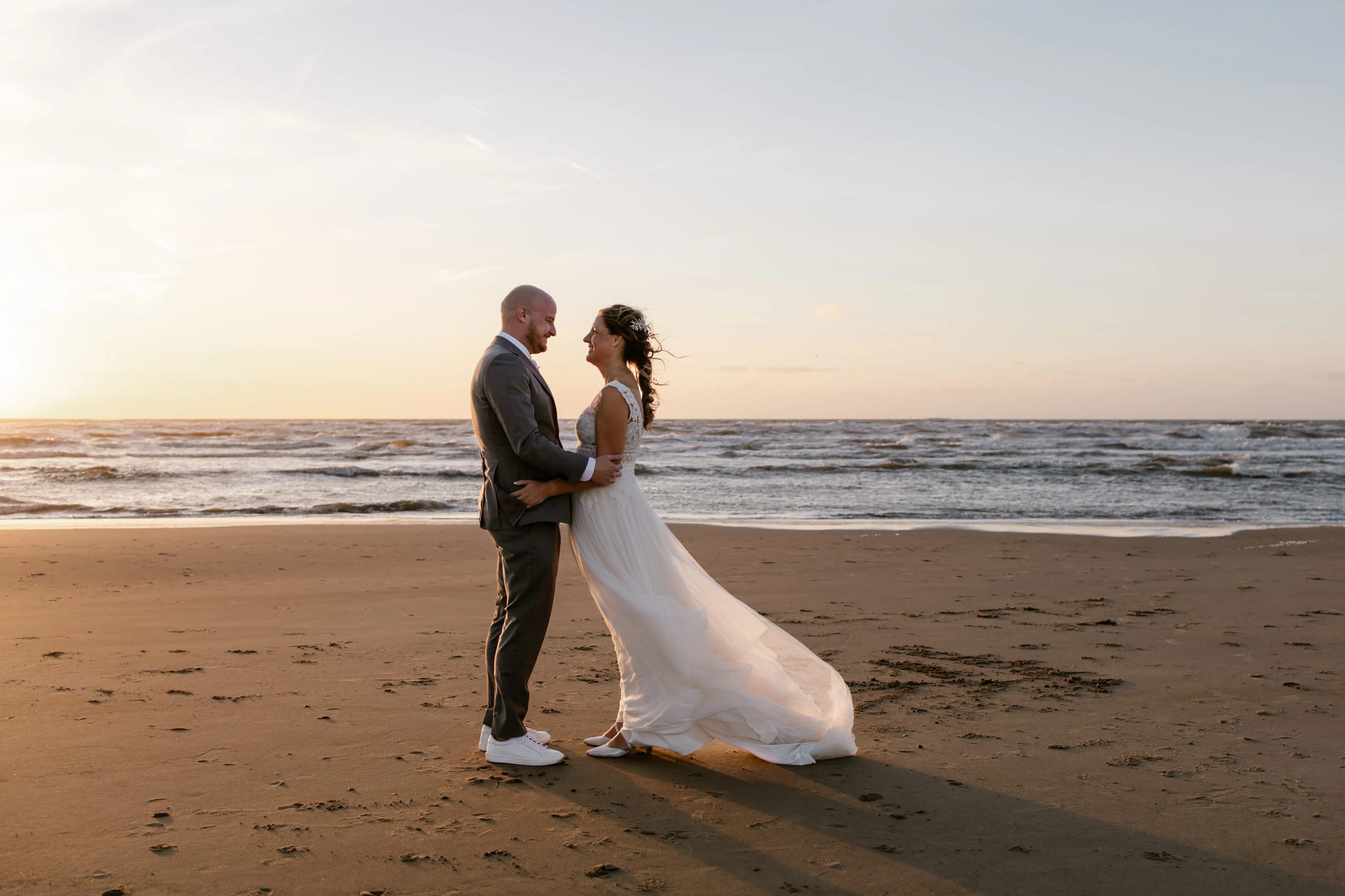 De bruid Denise geniet van de zeebries in haar haren op het strand