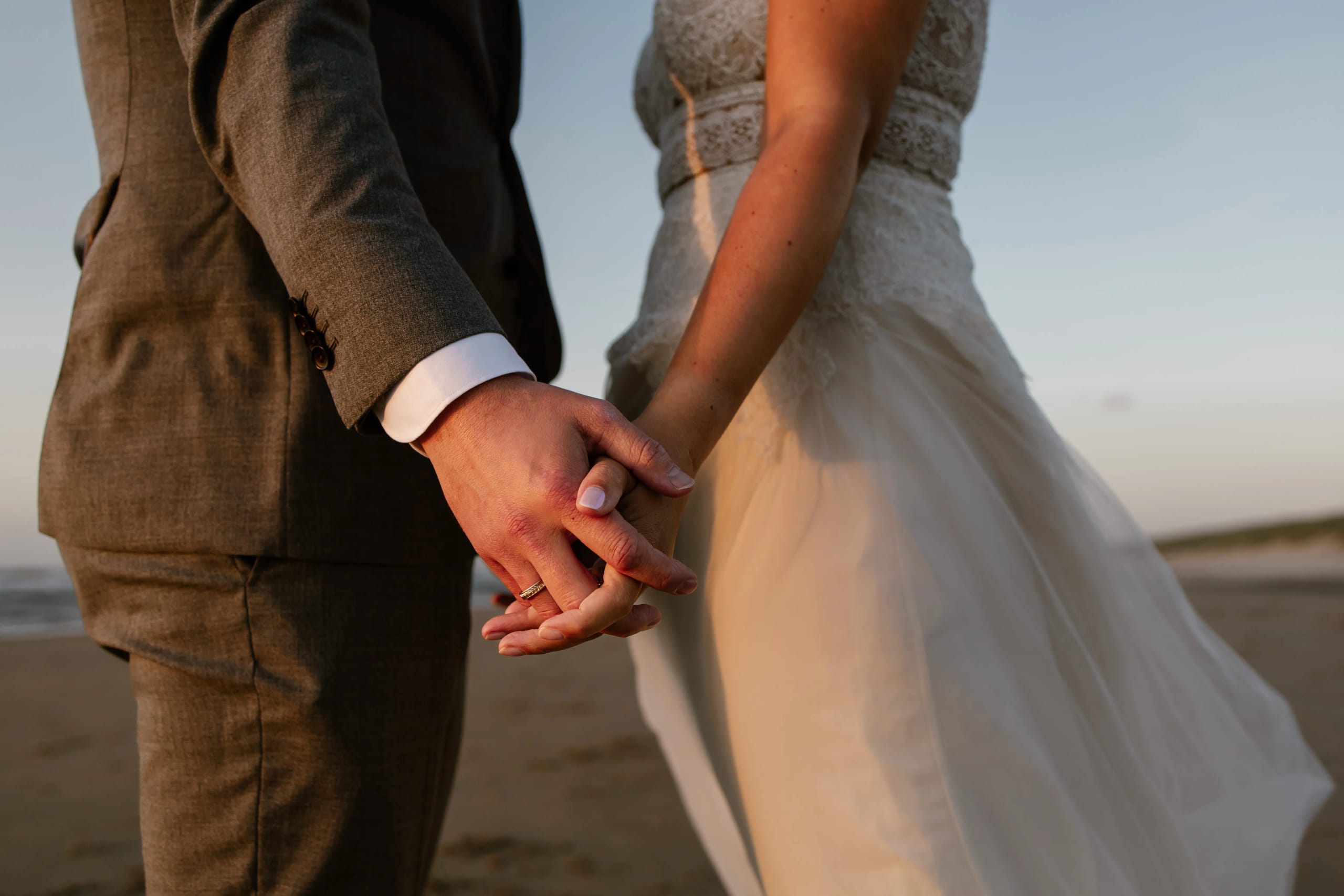 Zwart-wit detail of the in elkaar gestrengelde handen van het bruidspaar met trouwringen