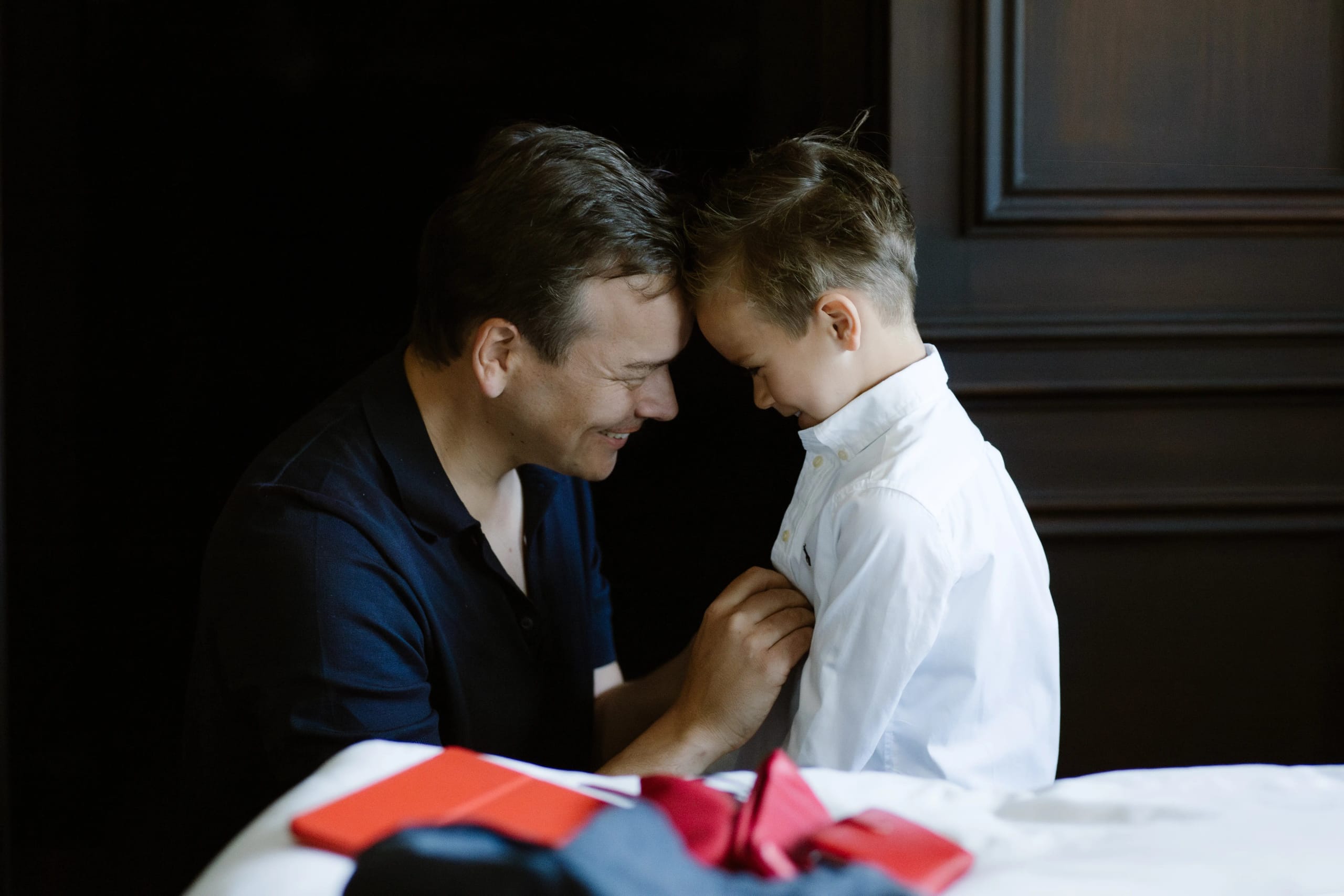 Vader helpt zijn jonge zoon met zijn witte overhemd tijdens de voorbereidingen van de bruiloft