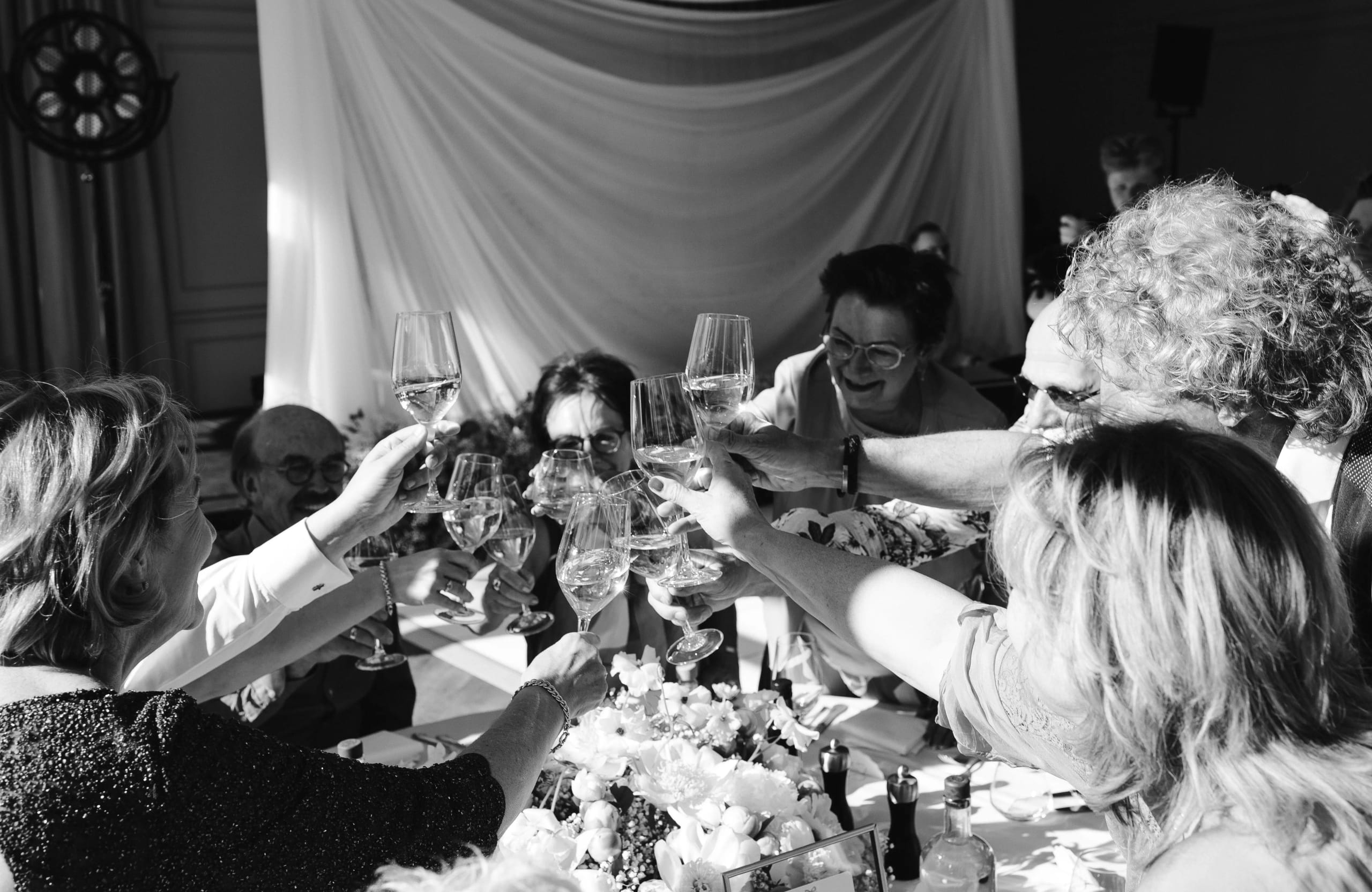 Gasten proosten vrolijk met wijnglazen aan een feestelijk gedekte tafel op een bruiloft