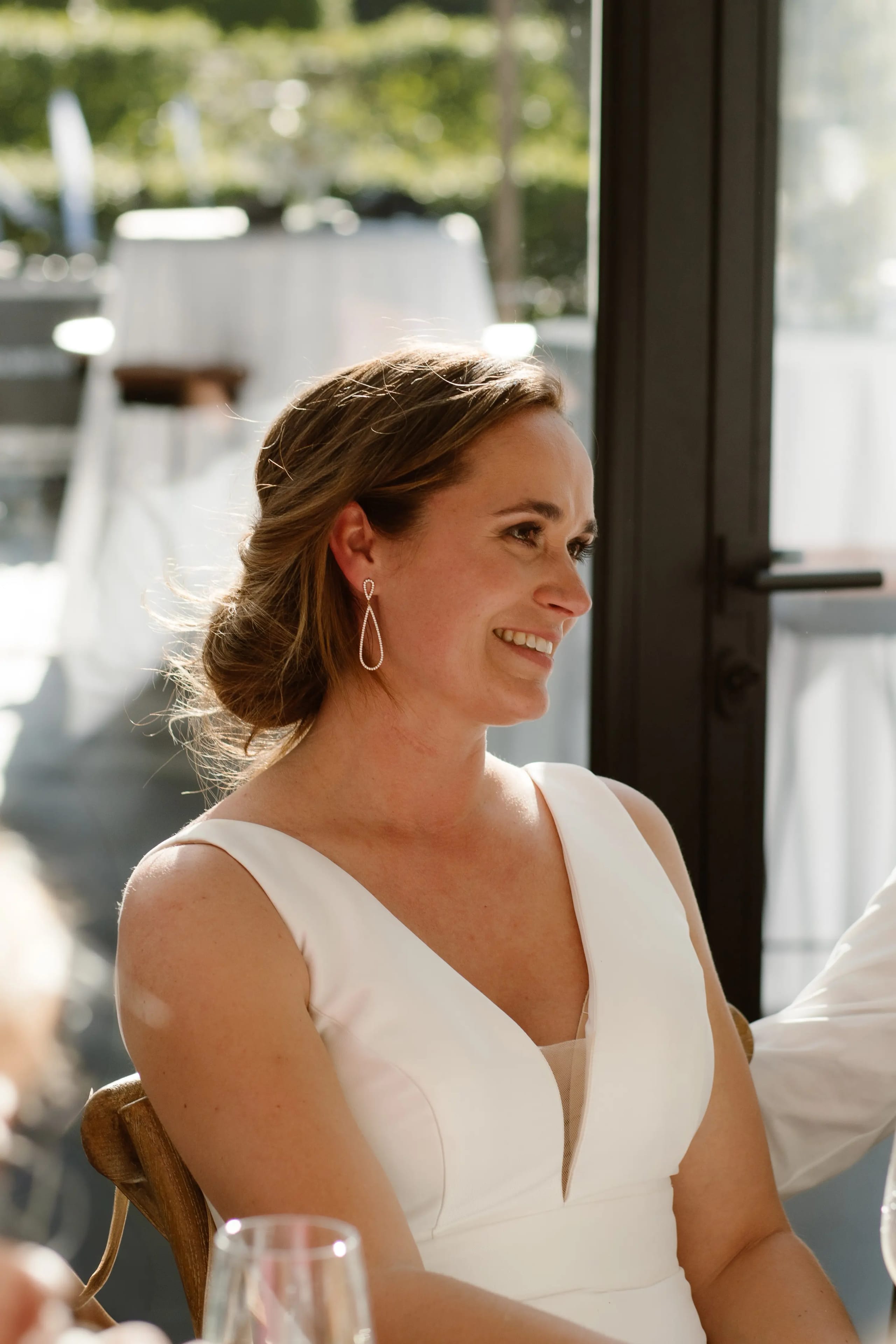 Portret van de lachende bruid die geniet van de sfeer aan tafel
