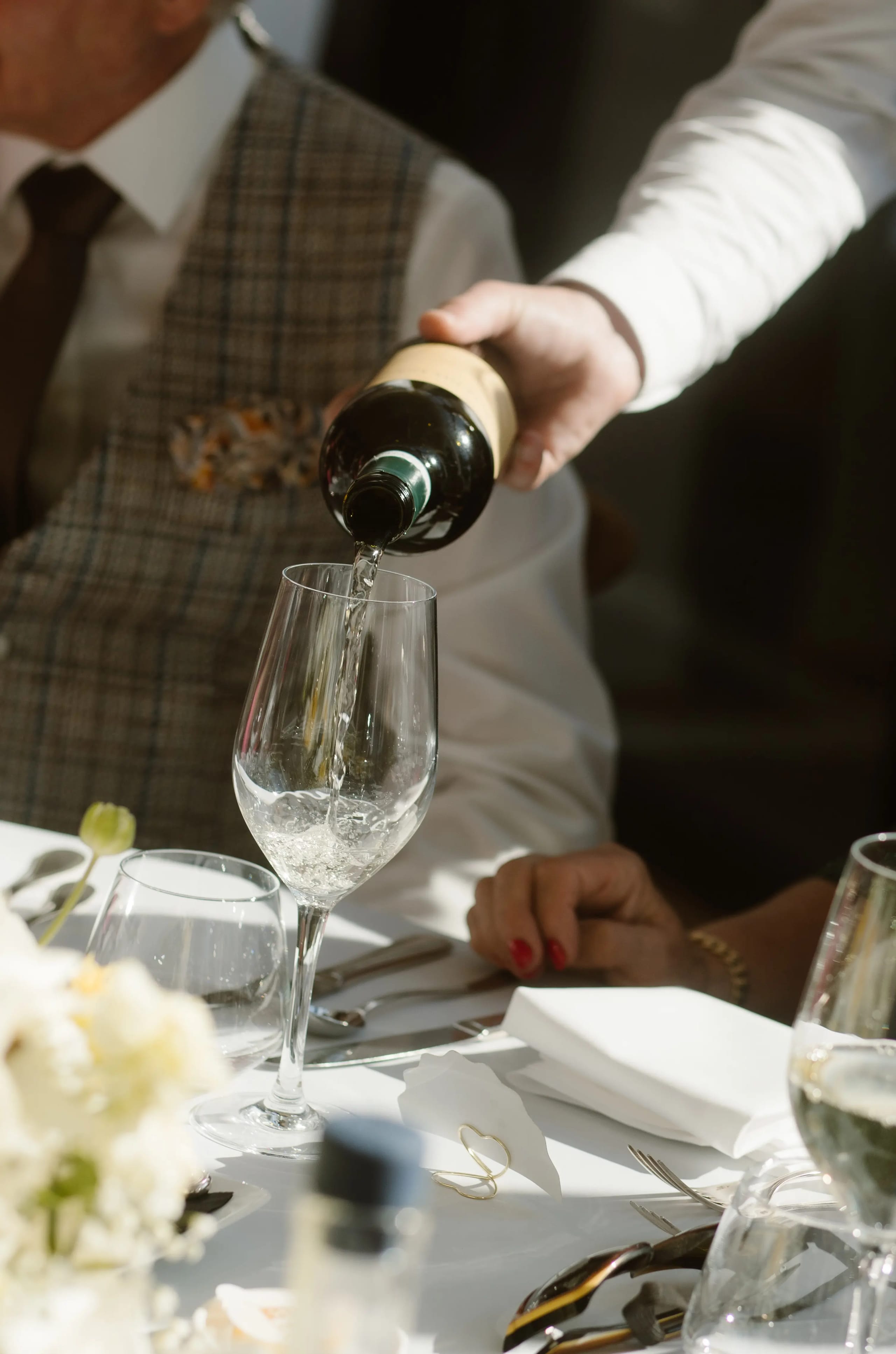 Detail van witte wijn die wordt ingeschonken in een glas aan een gedekte tafel