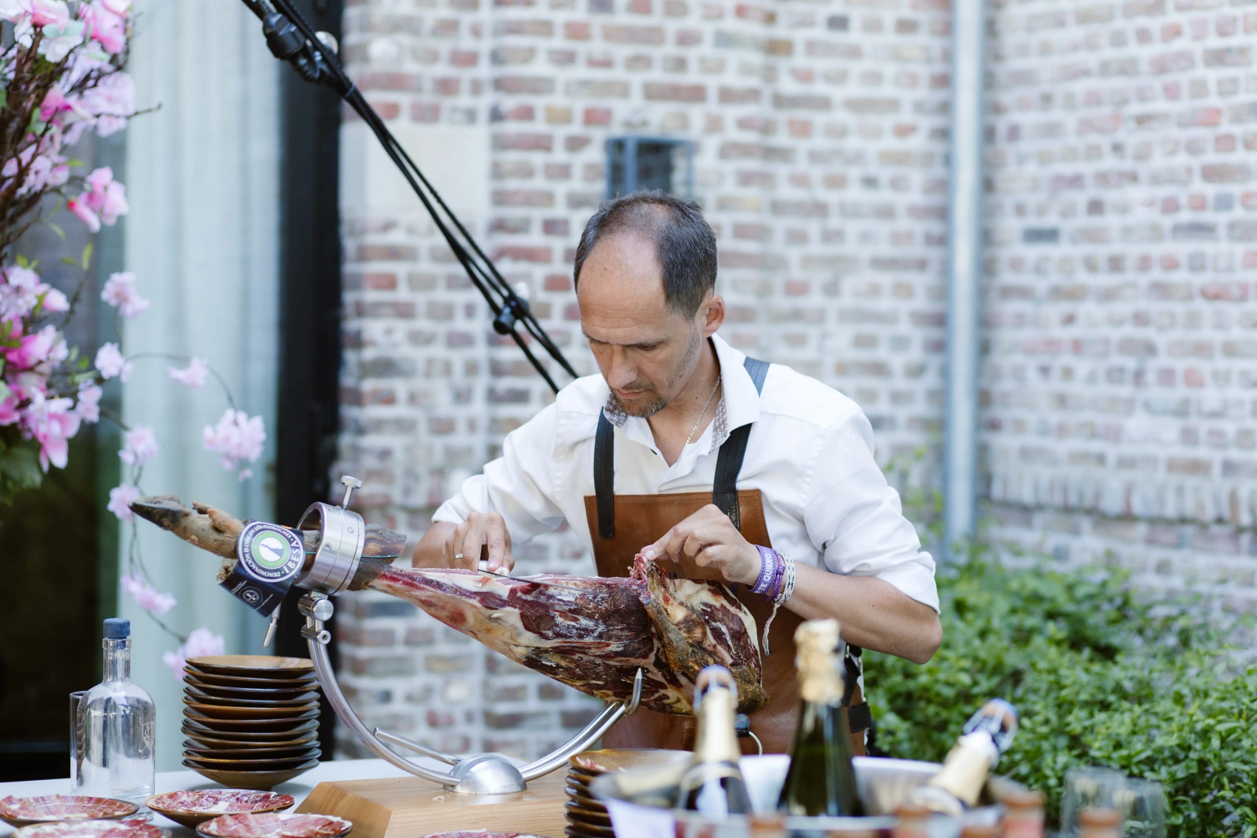 Een kok snijdt een grote ham aan voor de gasten tijdens de bruiloftborrel