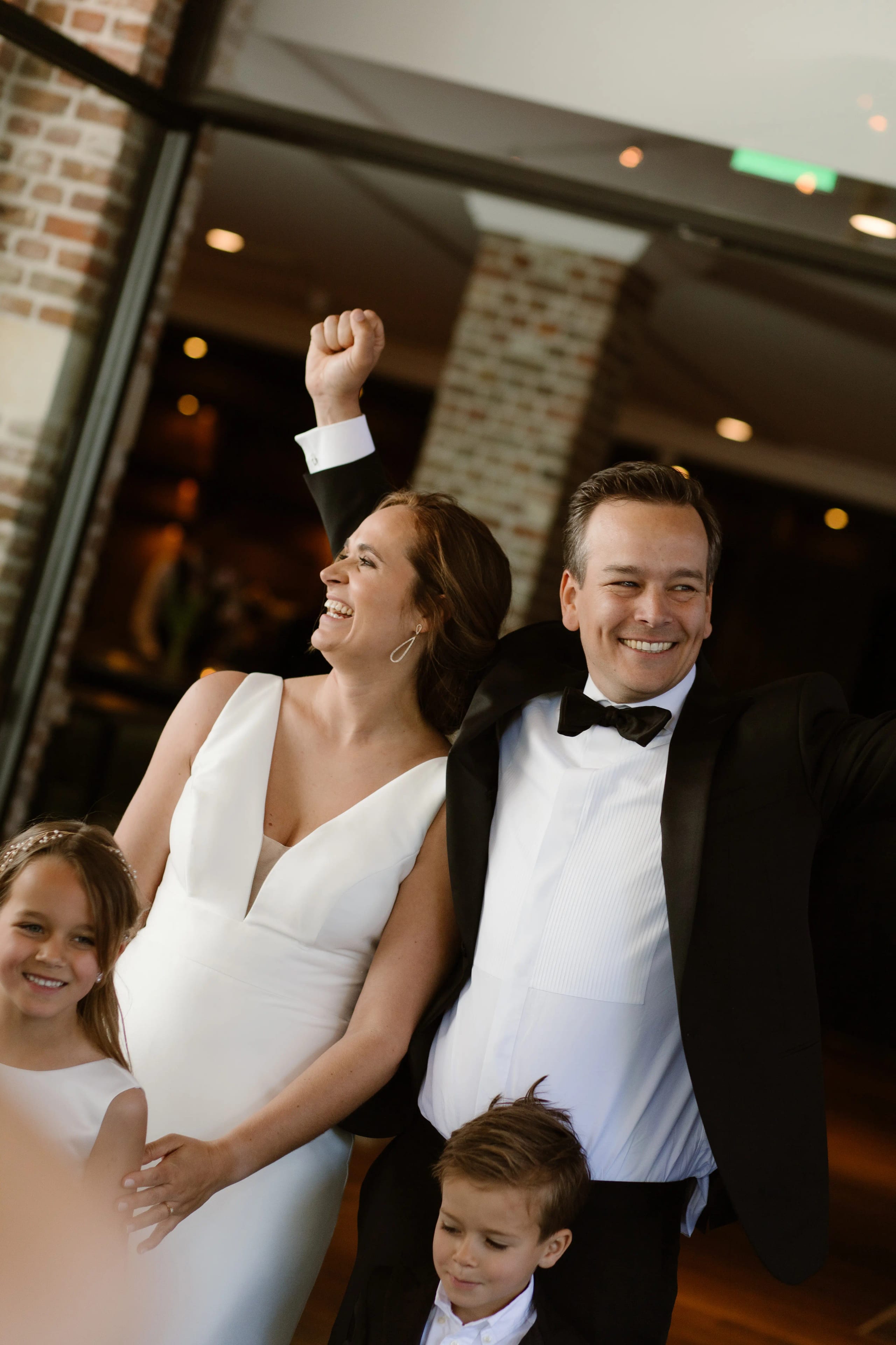 Bruidspaar viert feest met hun gasten en steekt hun handen in de lucht van blijdschap
