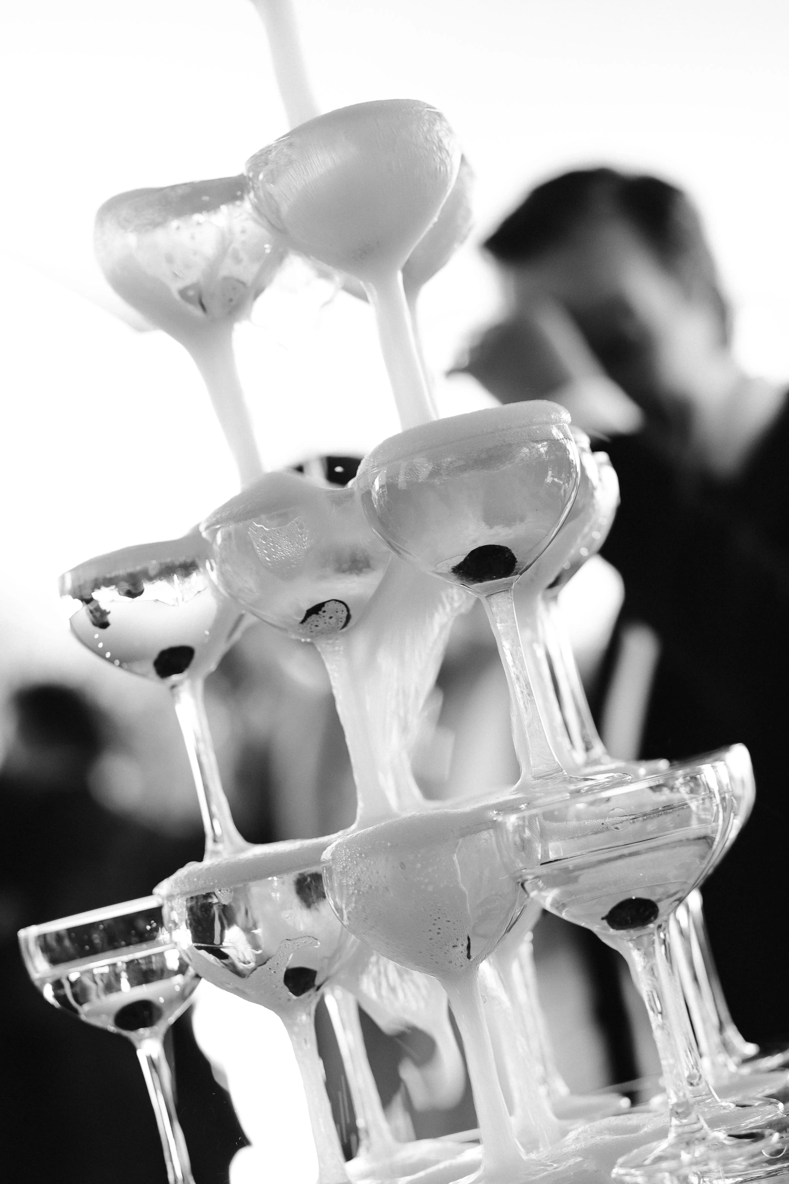 Close-up van champagne die van glas naar glas stroomt in een champagnetoren in zwart-wit