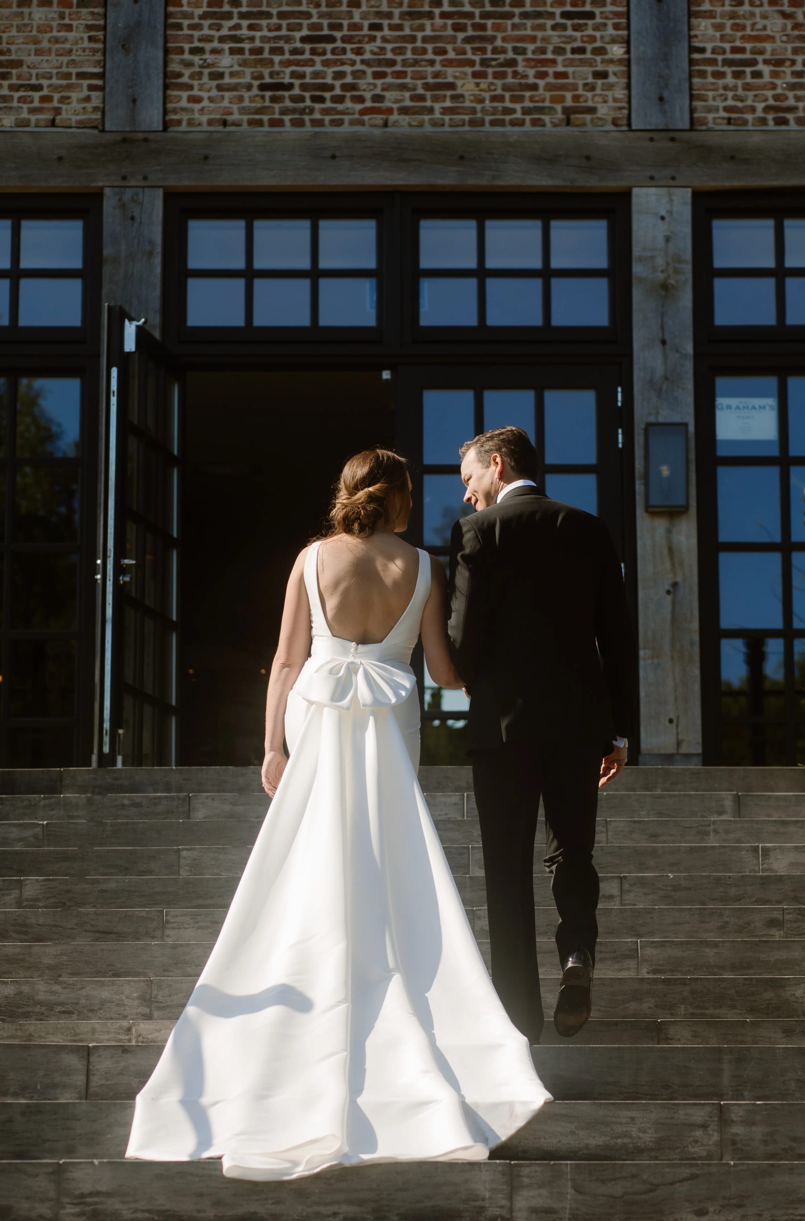 Bruidspaar loopt de trap op naar de ingang van een prachtig landhuis