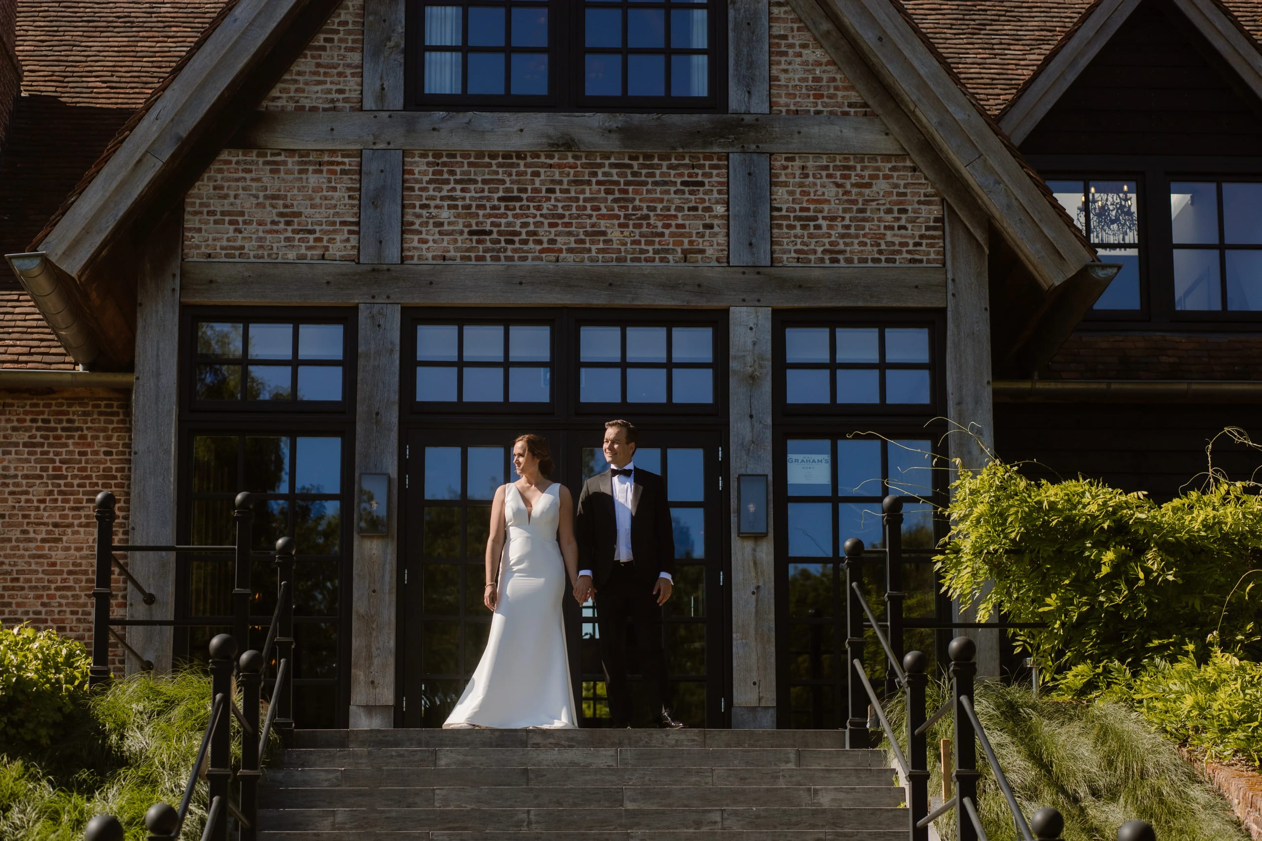 Bruid en bruidegom kijken elkaar aan op de trap voor de entree van de trouwlocatie