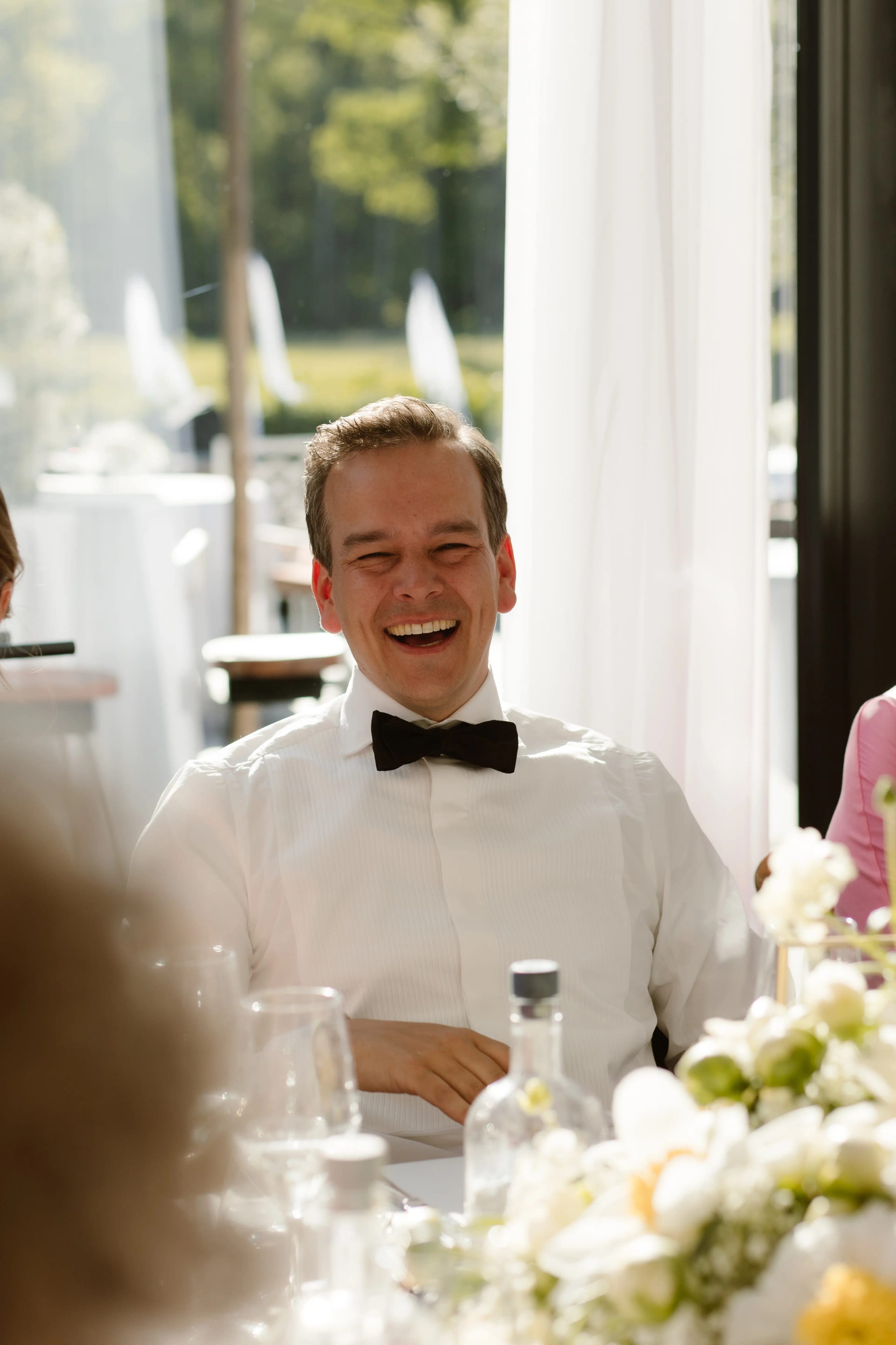 De bruidegom lacht hartelijk tijdens een toespraak bij het huwelijksdiner