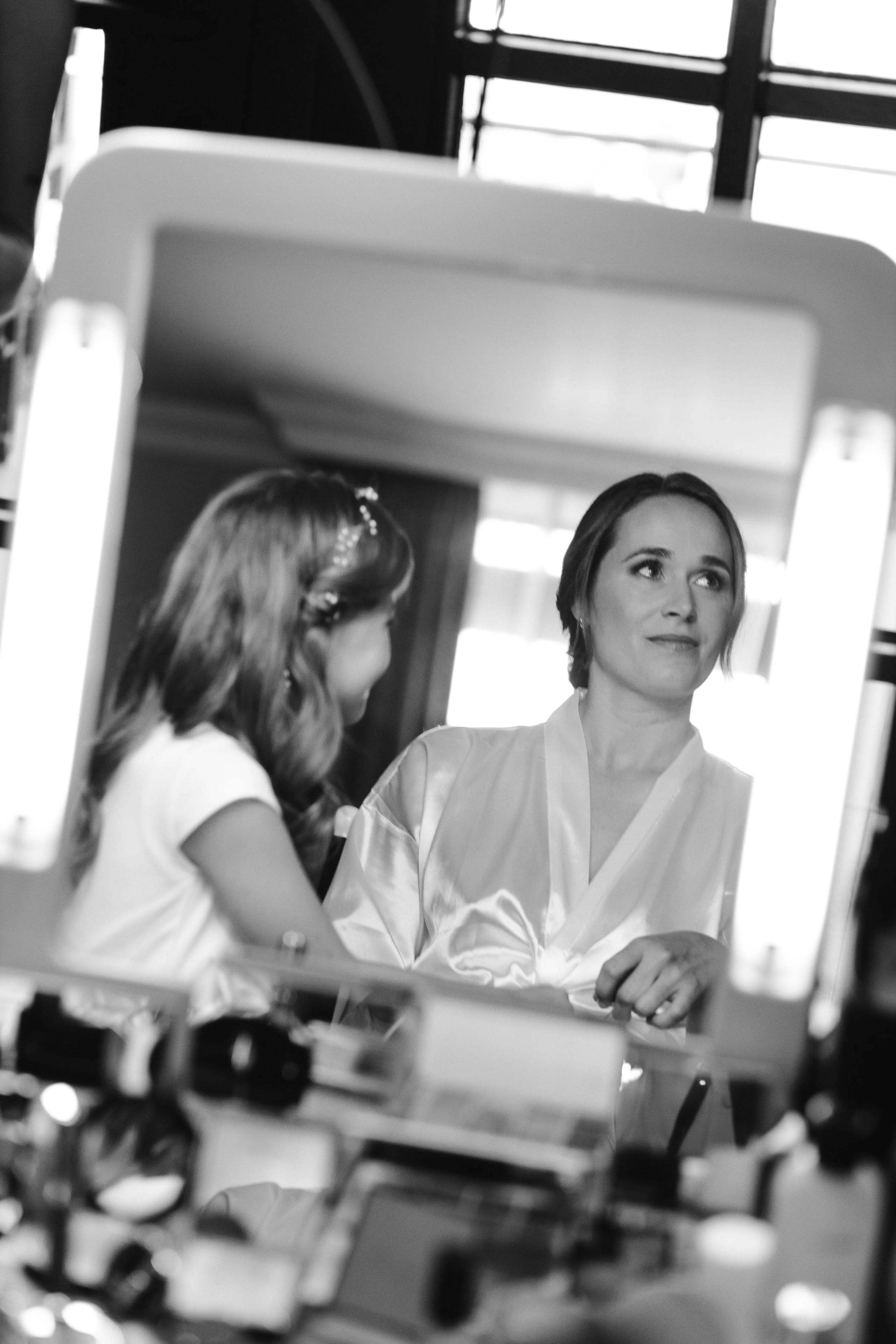 Zwart-wit reflectie van de bruid in de spiegel tijdens de visagie en haarstyling