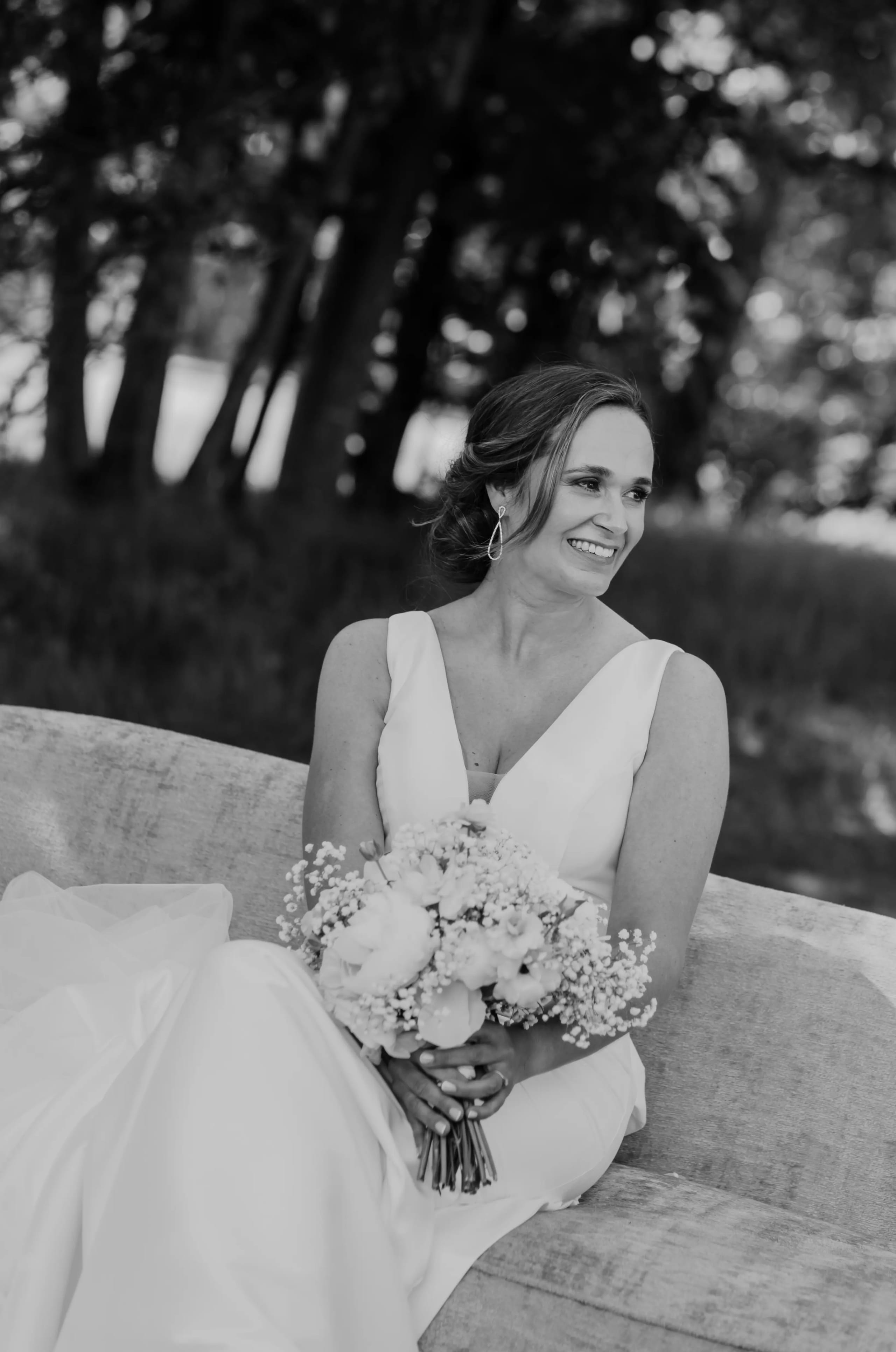 Zwart-wit portret van de bruid die houdt haar boeket vast zittend op een bankje