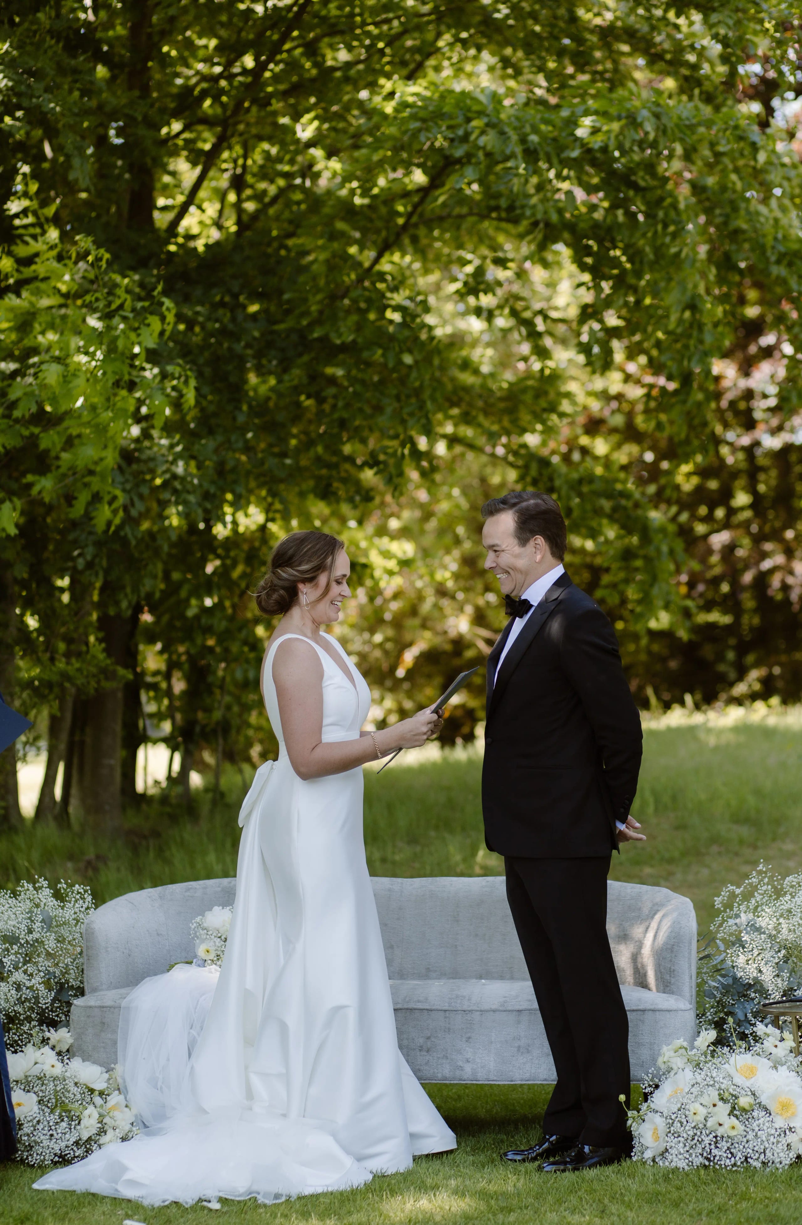 Het bruidspaar staat tegenover elkaar in de tuin en houdt elkaars hands vast