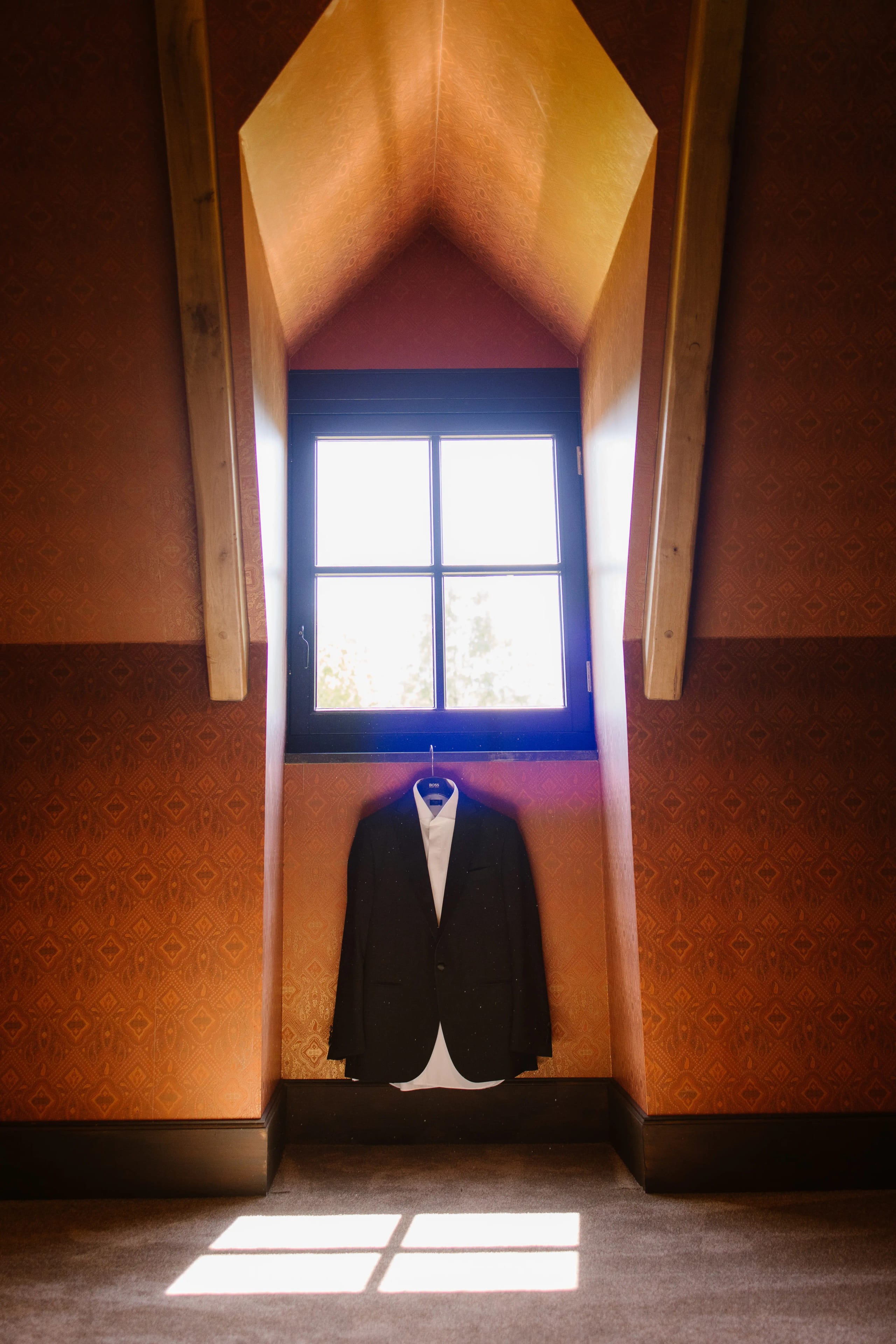 Het trouwpak van de bruidegom hangt klaar voor een raam in een kasteelachtige kamer