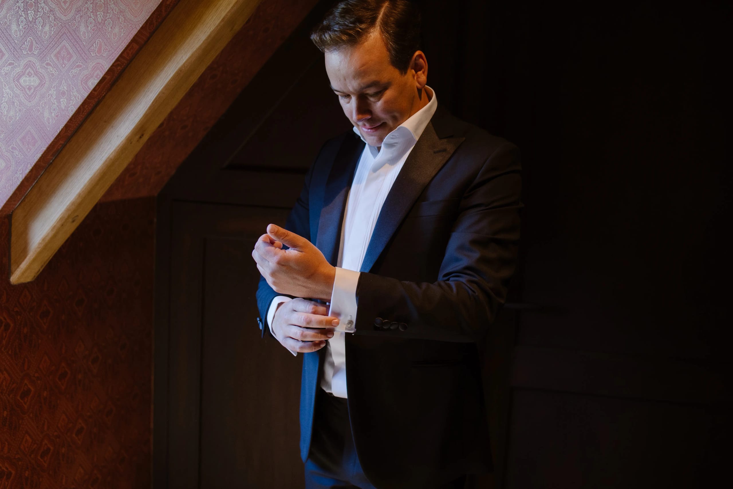 De bruidegom trekt zijn manchetknoopjes recht als finishing touch van zijn pak