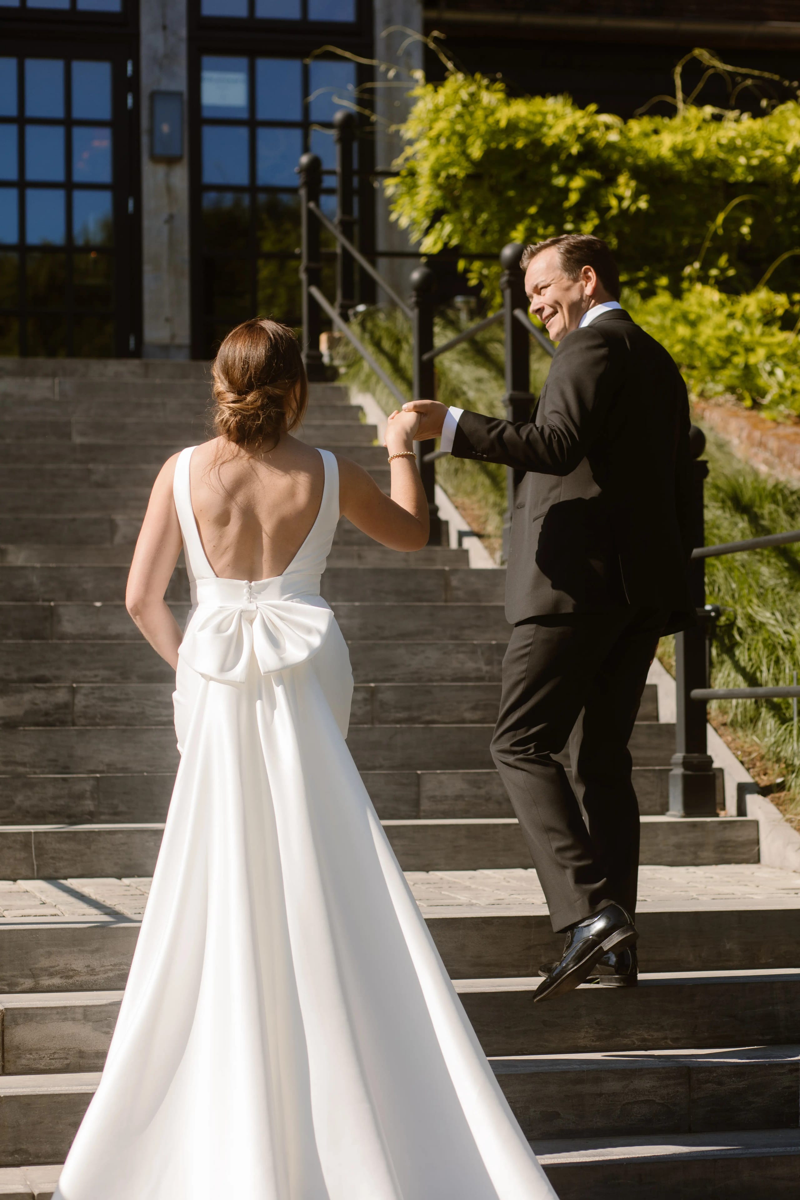 Het bruidspaar loopt hand in hand de trap op bij het landhuis