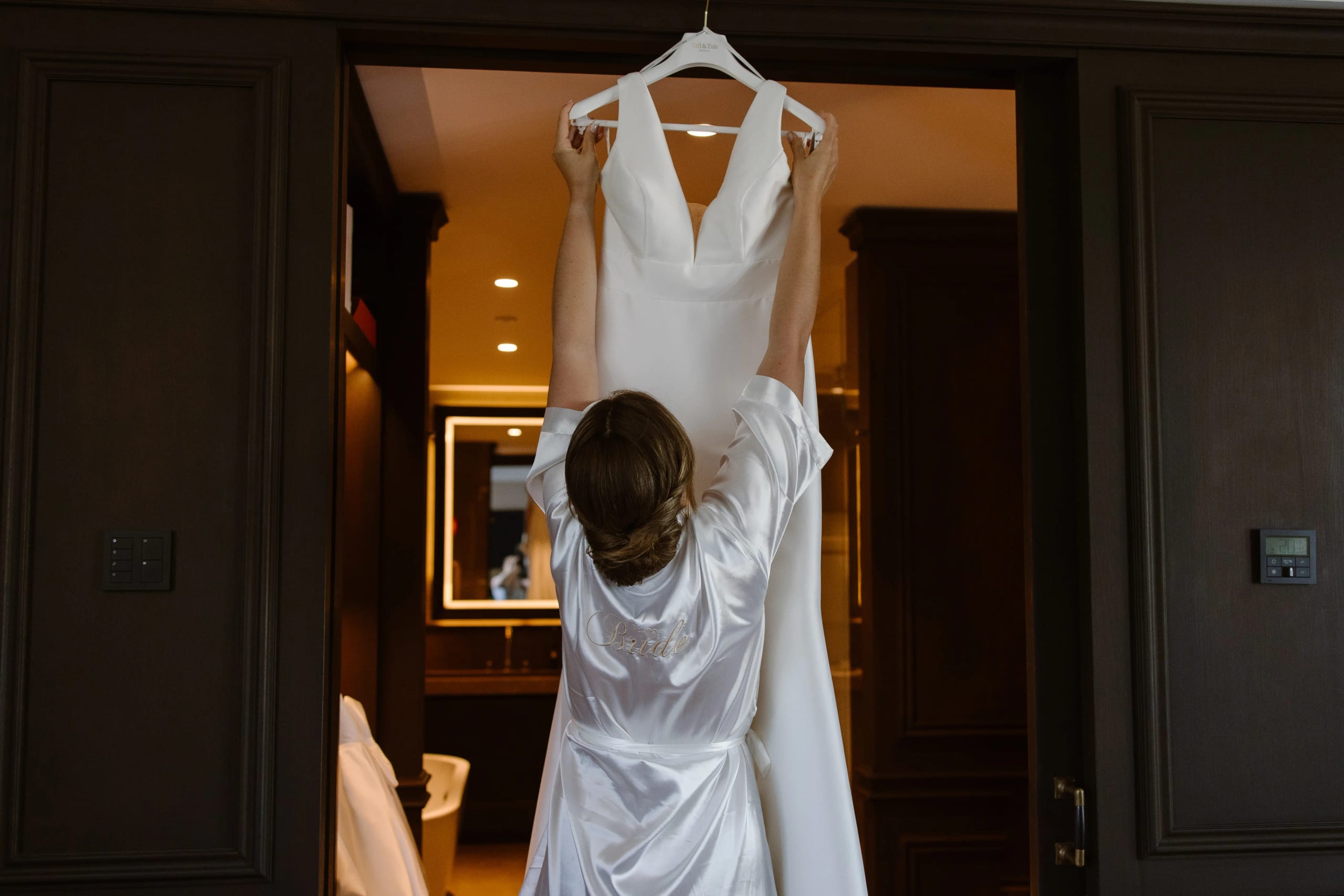 De bruid bekijkt haar trouwjurk die klaar hangt voor de grote dag