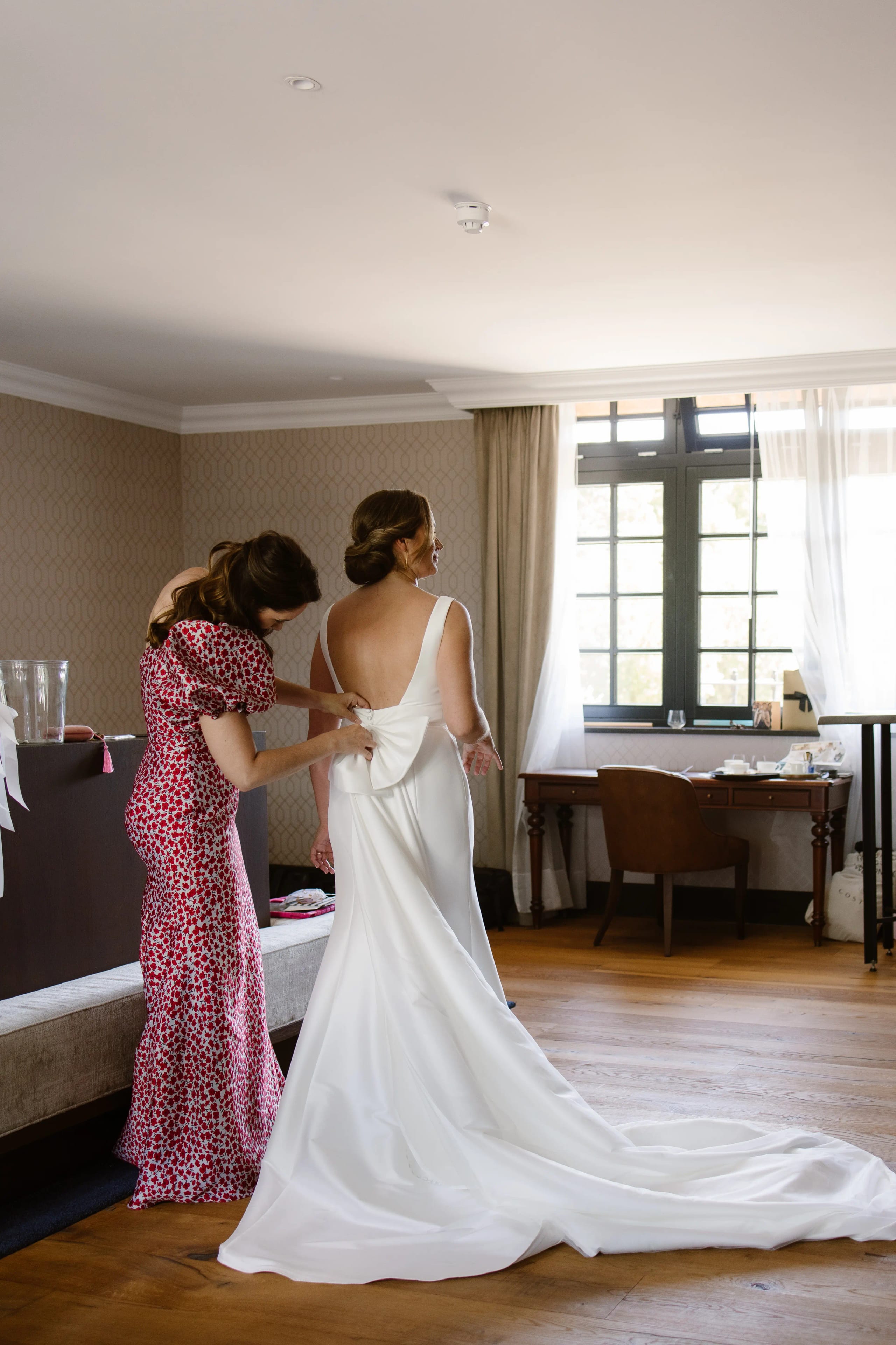 Vriendin helpt de bruid met het aantrekken van haar jurk en sleep