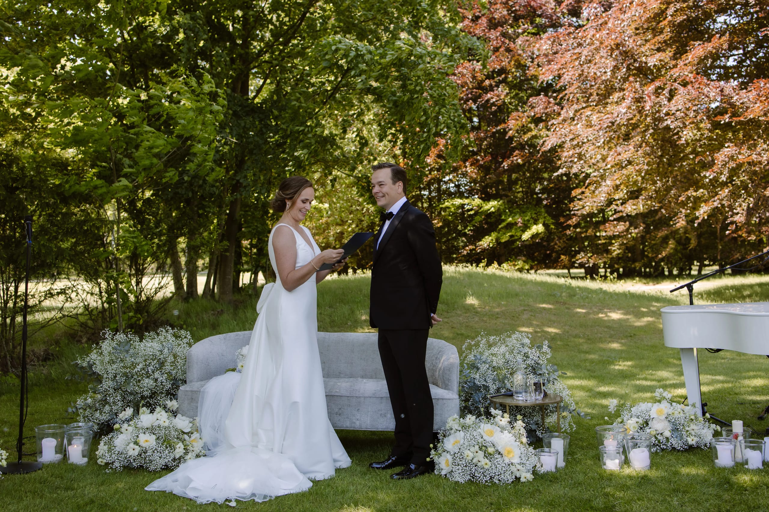 Het bruidspaar staat tegenover elkaar bij de buitenlocatie onder de bomen