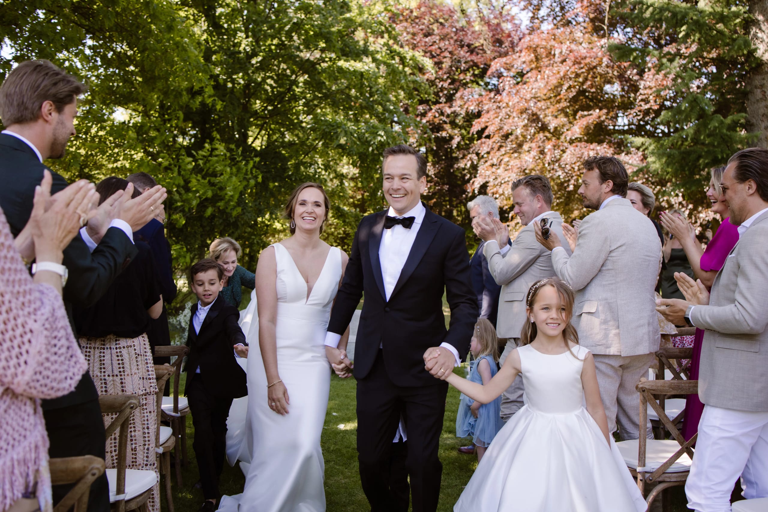Het kersverse bruidspaar loopt stralend door de blaadjes bij de uitgang van de ceremonie