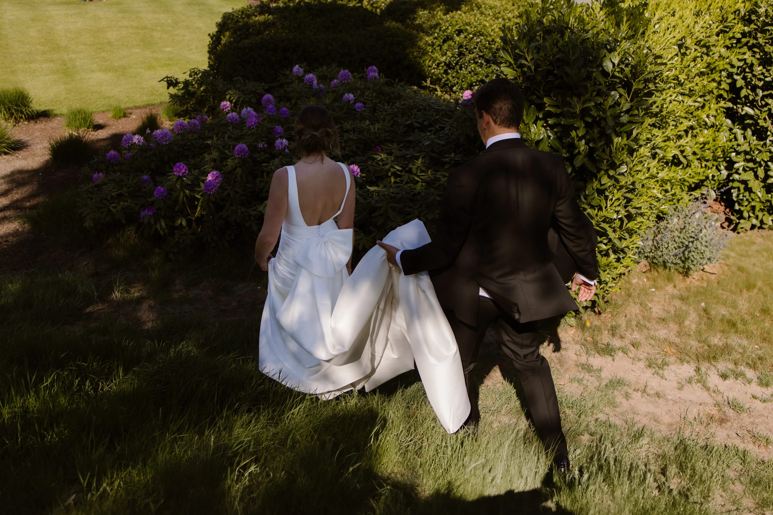 Bruid en bruidegom loopt hand in hand weg door het gras