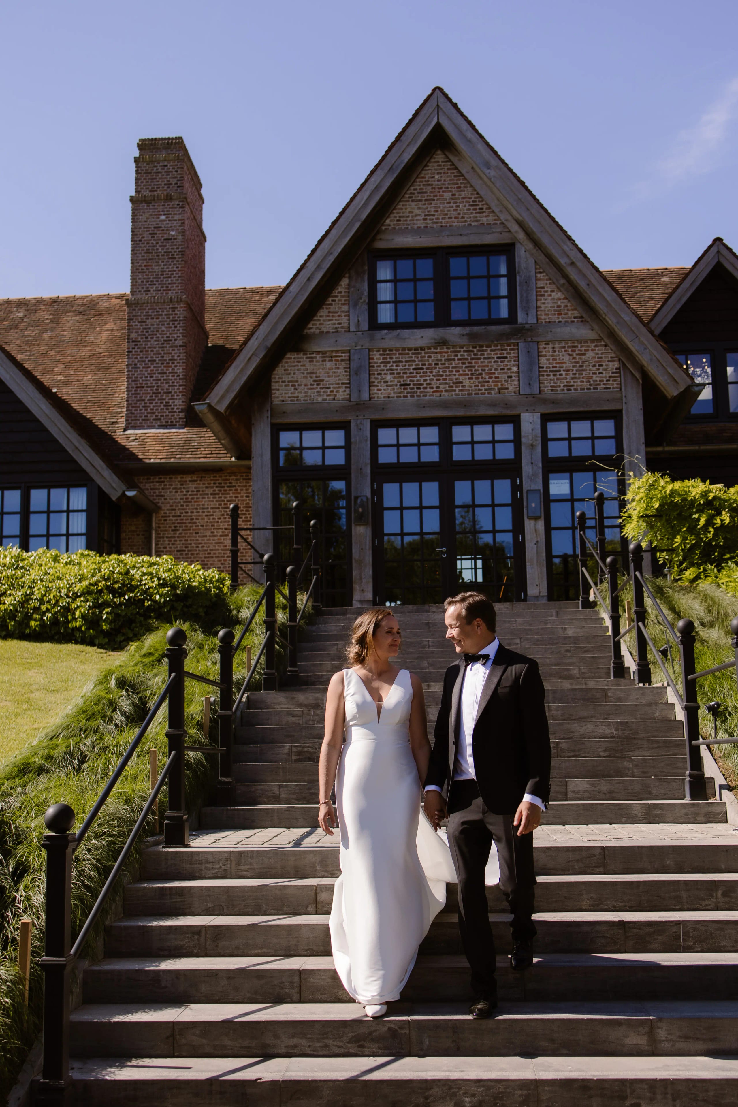 Het bruidspaar loopt de trap af naar hun gasten bij de feestlocatie