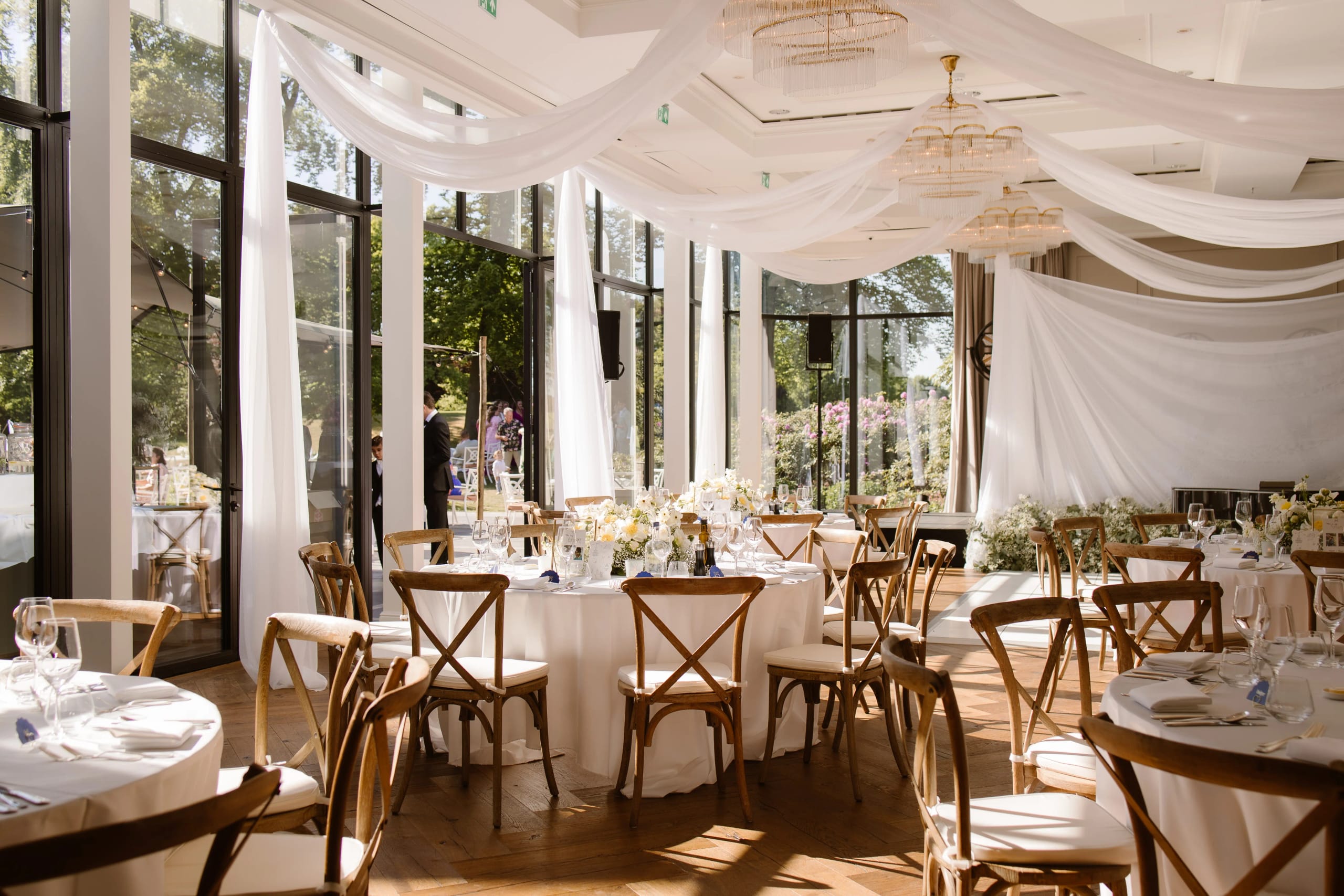 Elegant gedekte ronde tafels met bloemen in een lichte serre van het landhuis