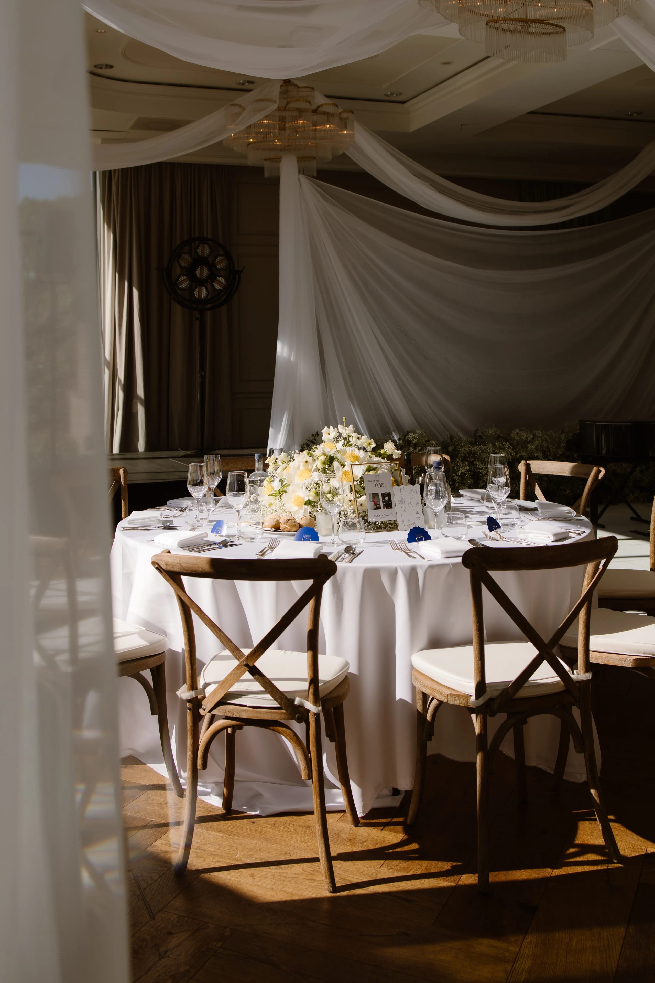 Detail van een ronde bruiloftstafel met wit textiel en verse bloemstukken