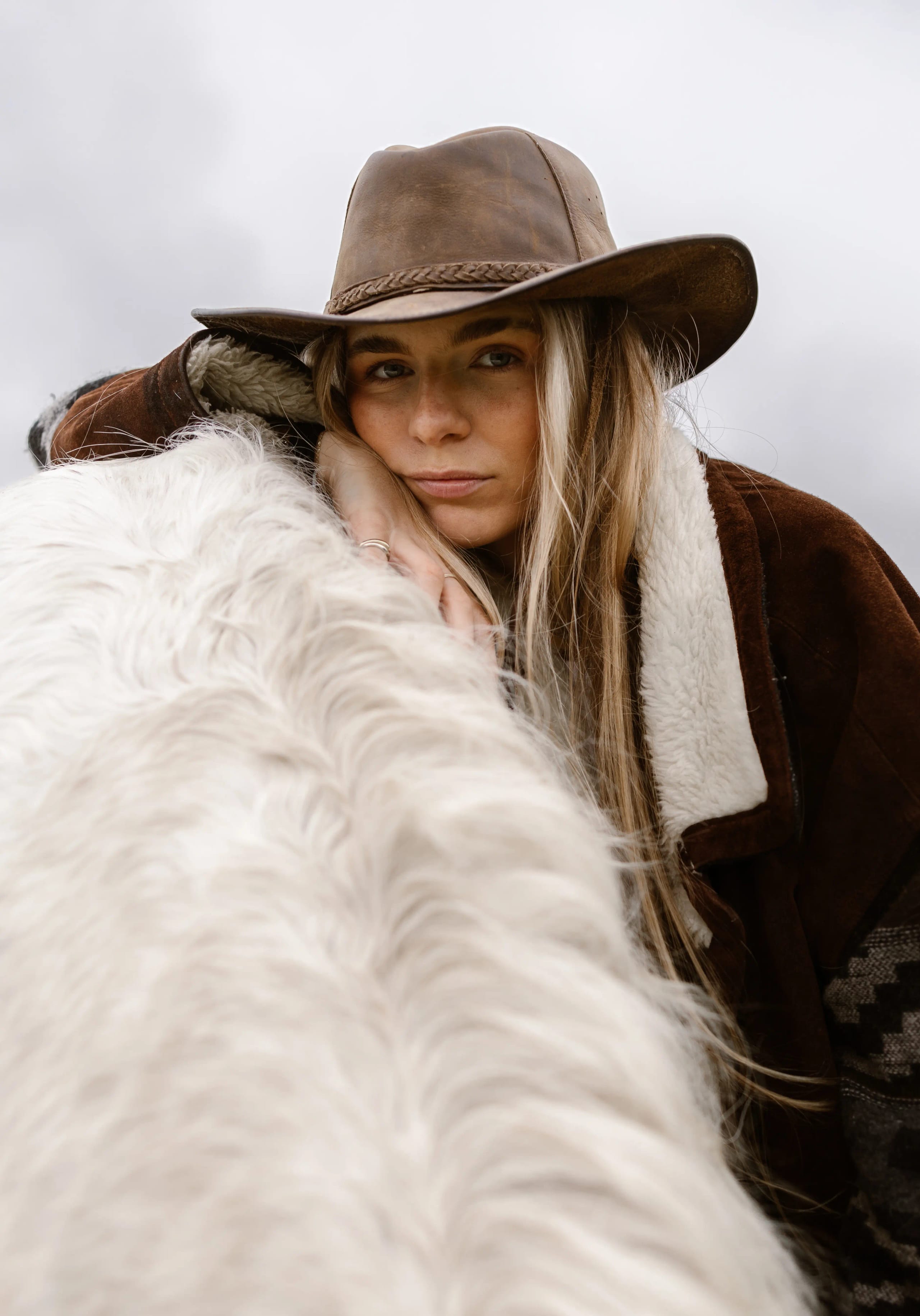 Lies Zhara rustend op de rug van een wit paard in de wei