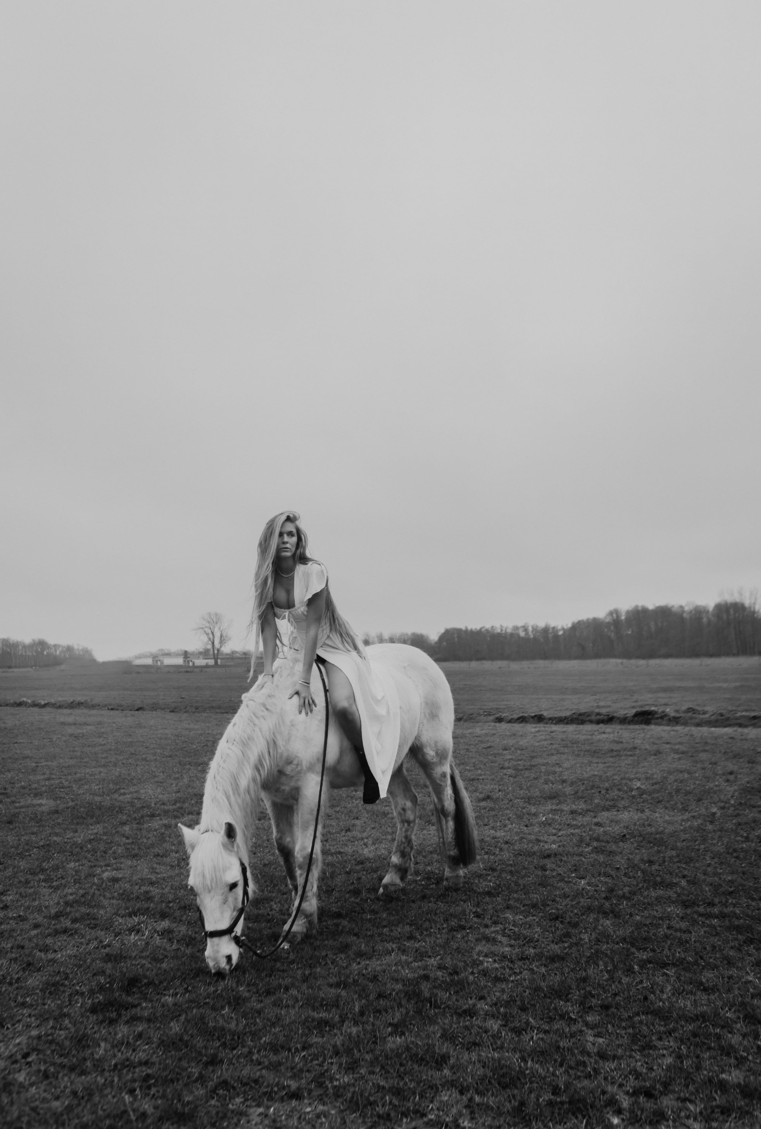 Lies Zhara rijdend op een wit paard in een open veld, zwart-wit